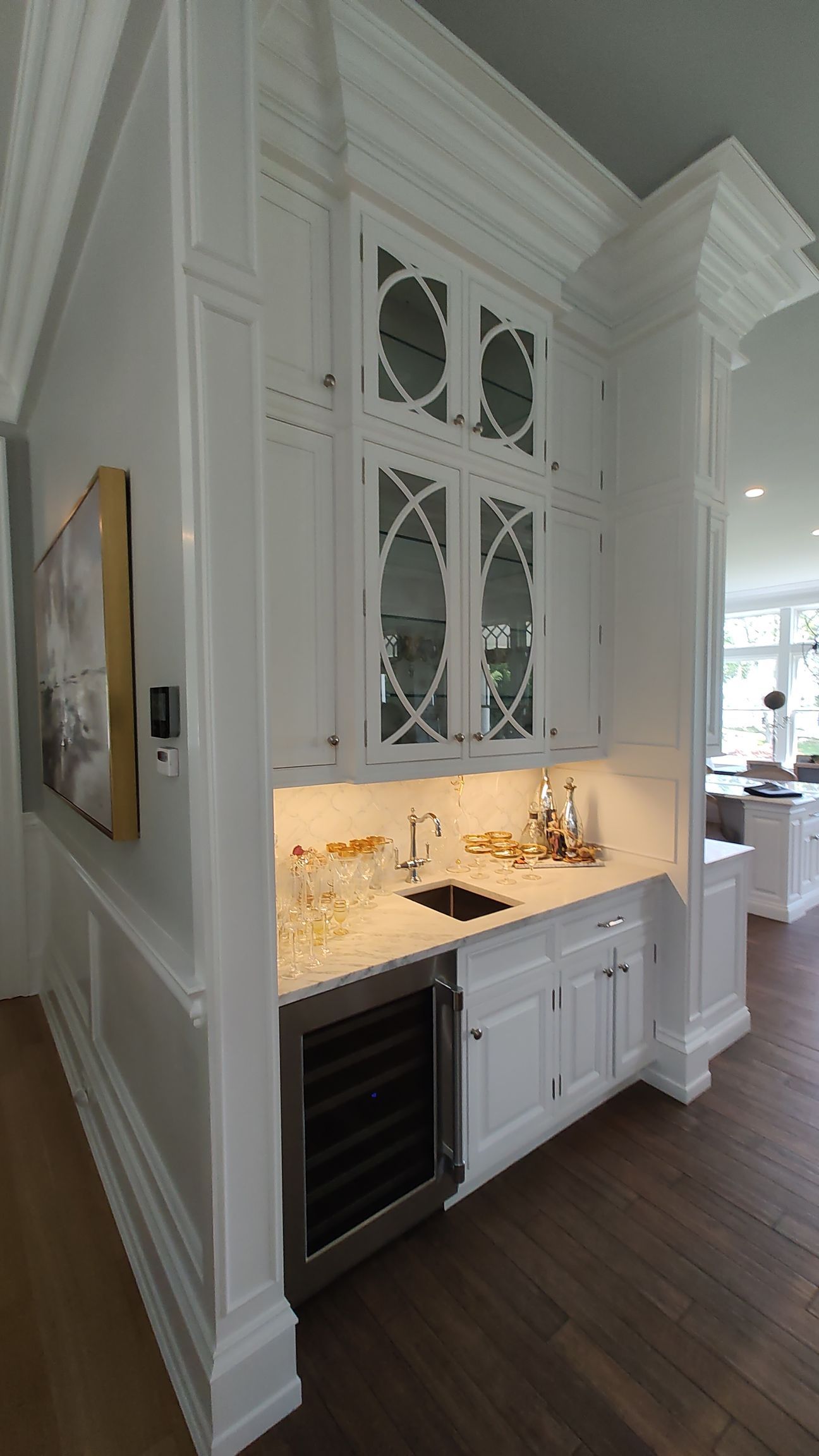 A kitchen with white cabinets, a sink, and a refrigerator.