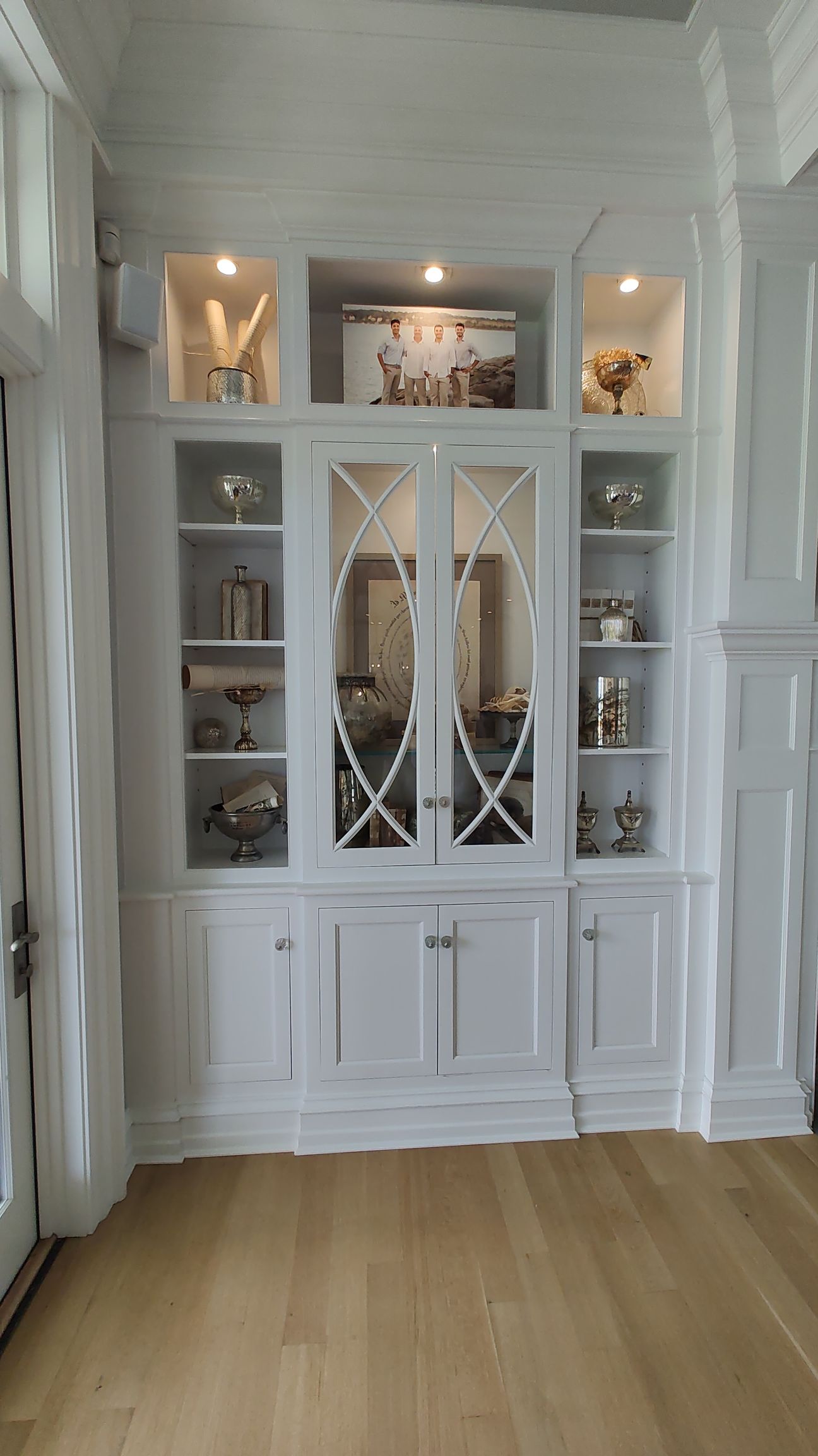 A living room with hardwood floors and white cabinets.
