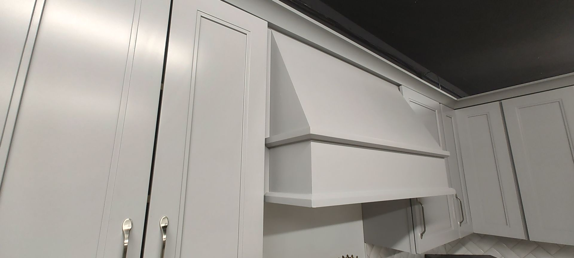 A kitchen with white cabinets and a black ceiling.