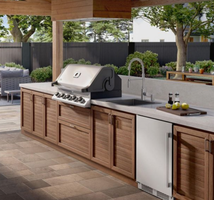 An outdoor kitchen with wooden cabinets and a grill