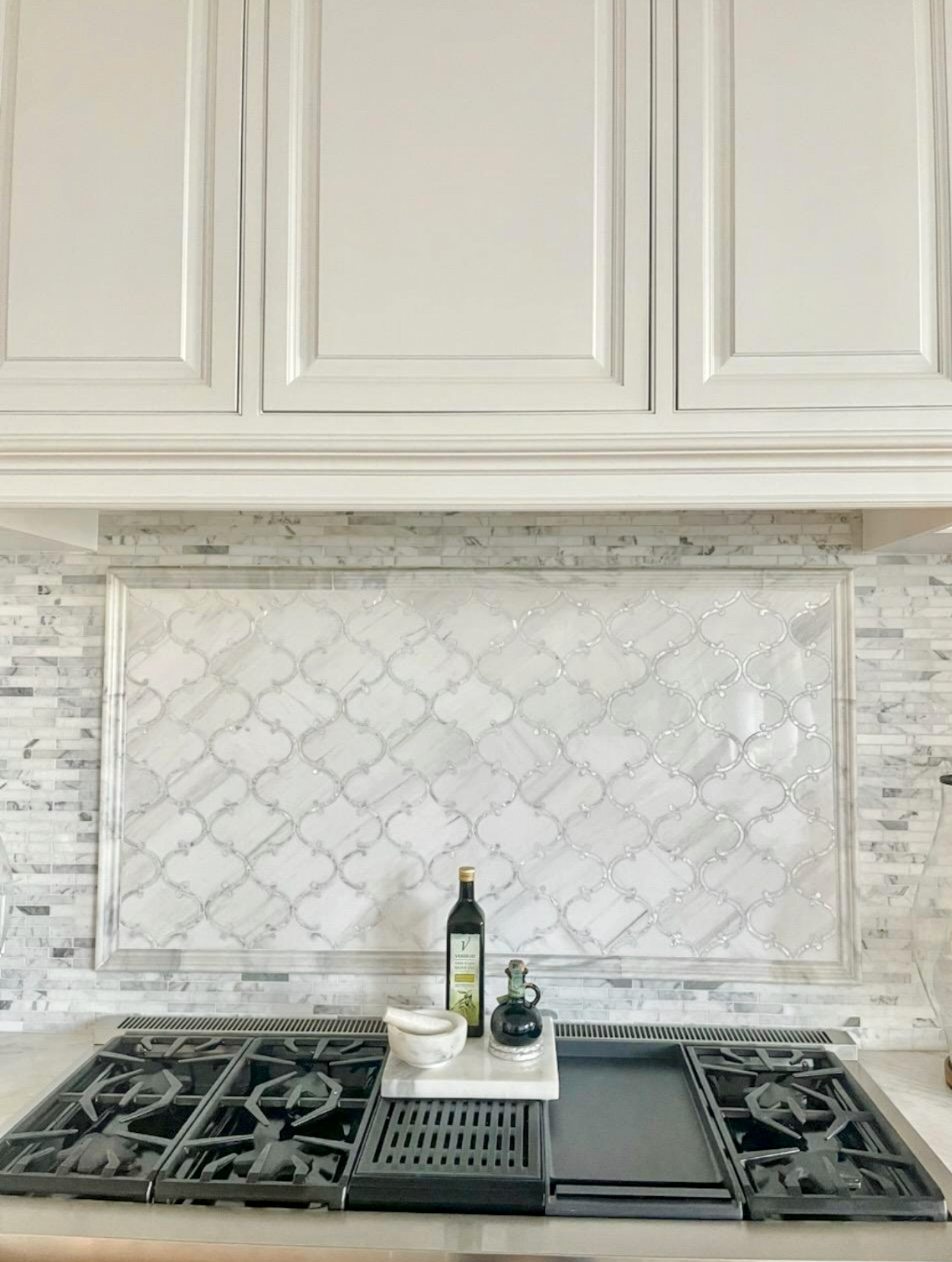 A kitchen with white cabinets and a stove top oven.