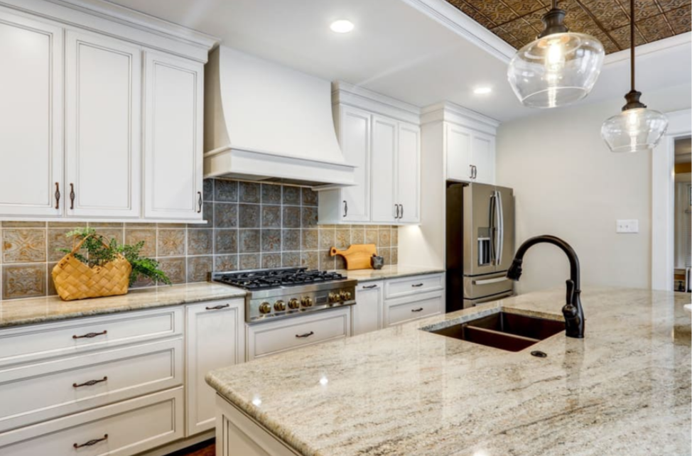 A kitchen with white cabinets, granite countertops, stainless steel appliances, and a sink.