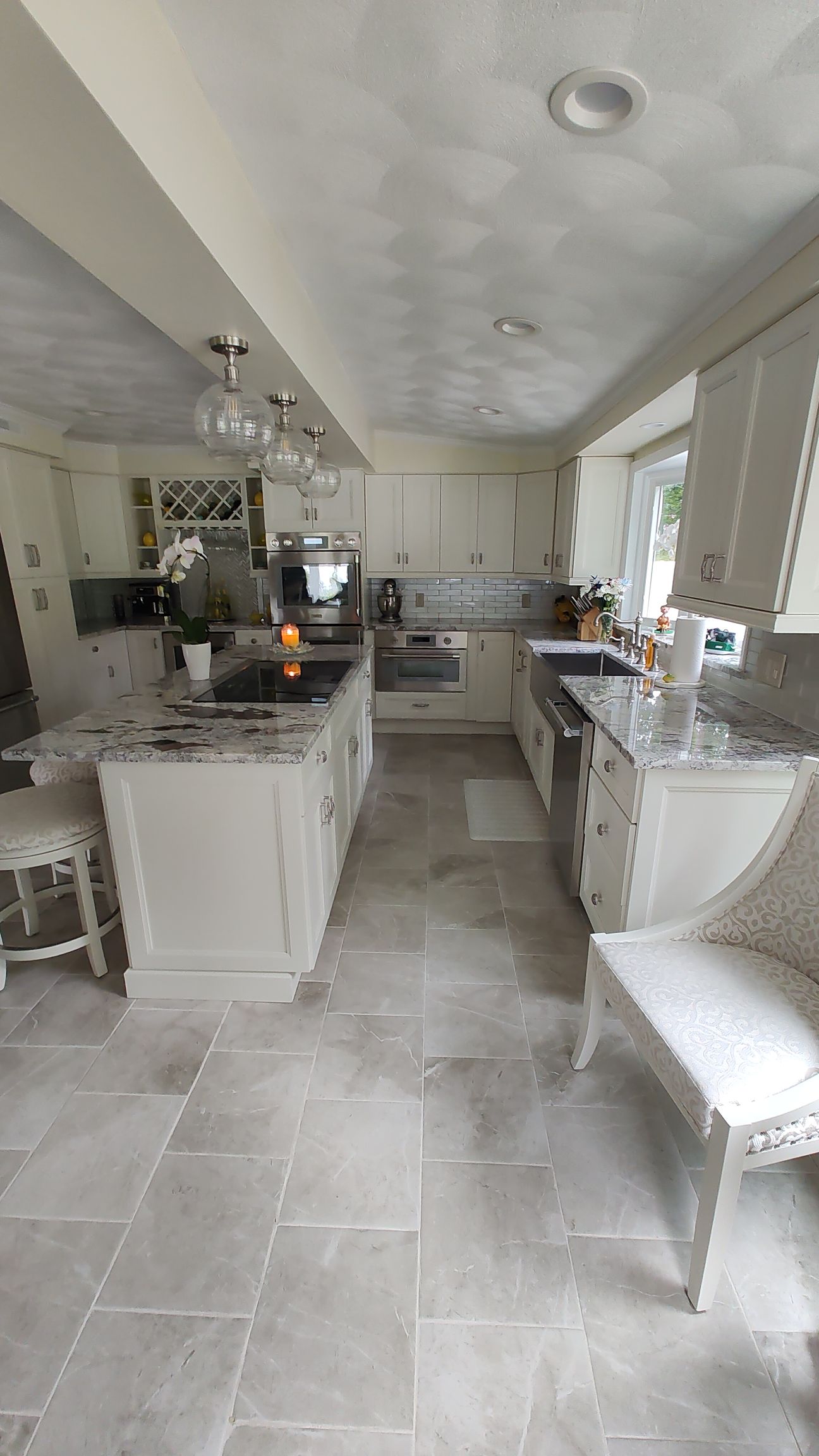 A kitchen with white cabinets, granite countertops, and stainless steel appliances.