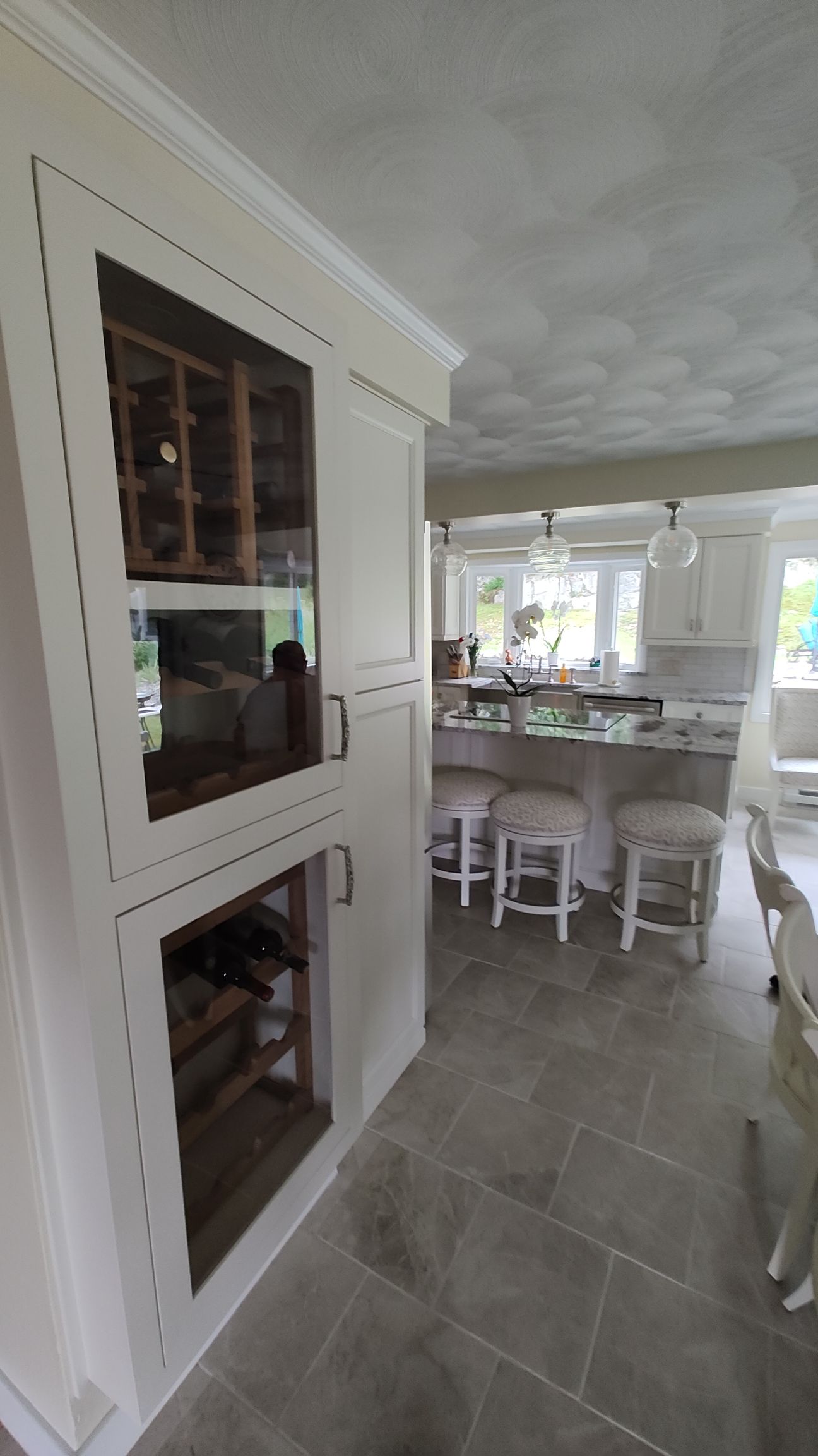 A kitchen with white cabinets and a wine rack.