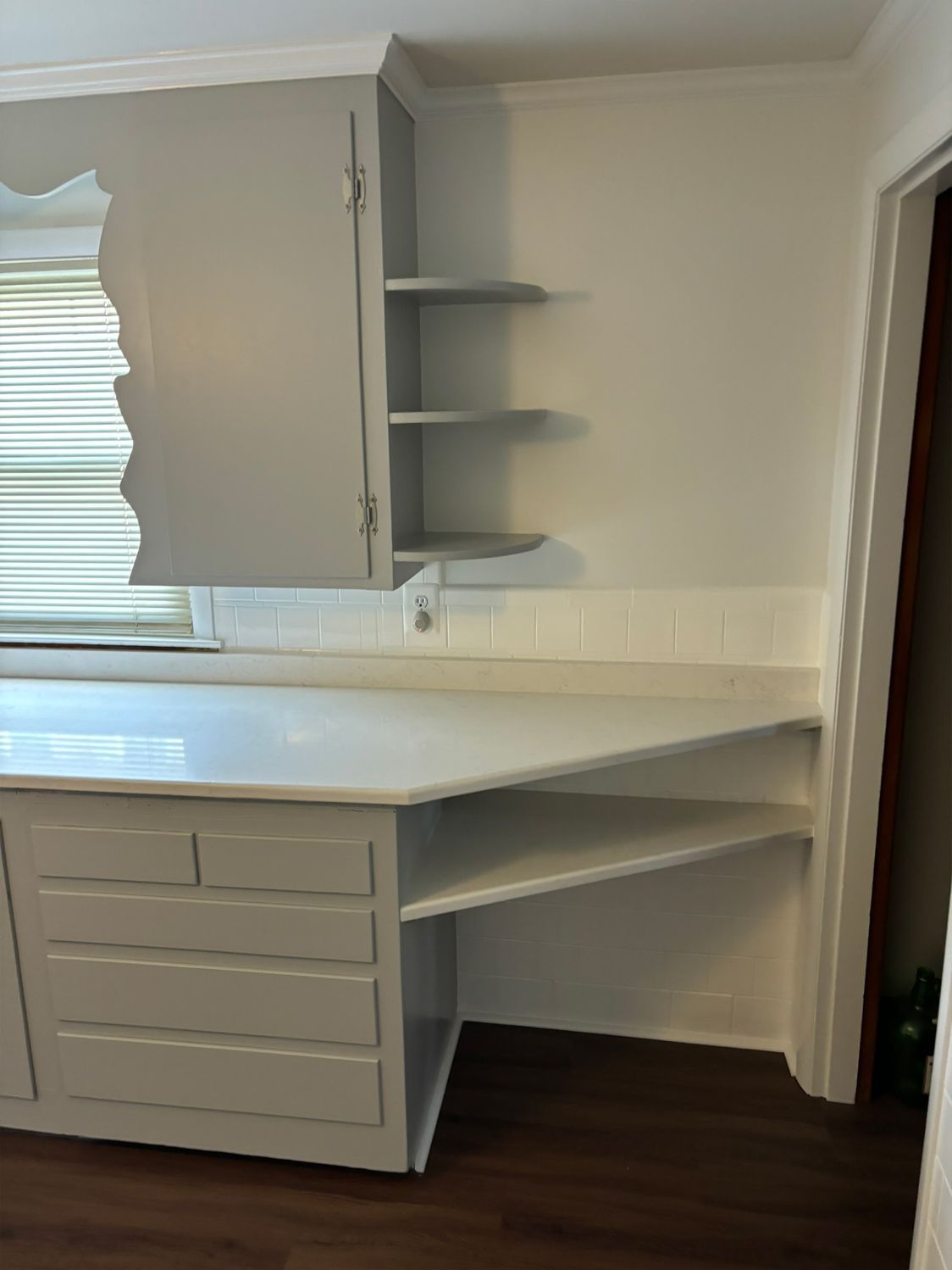 Gray kitchen cabinetry with counter, shelves, and a built-in desk area.