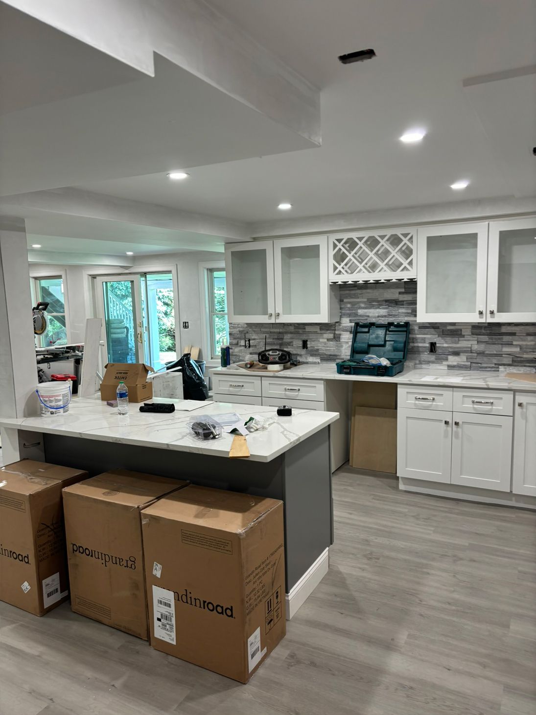 Kitchen with white cabinets, gray island, and light gray flooring; renovation in progress.