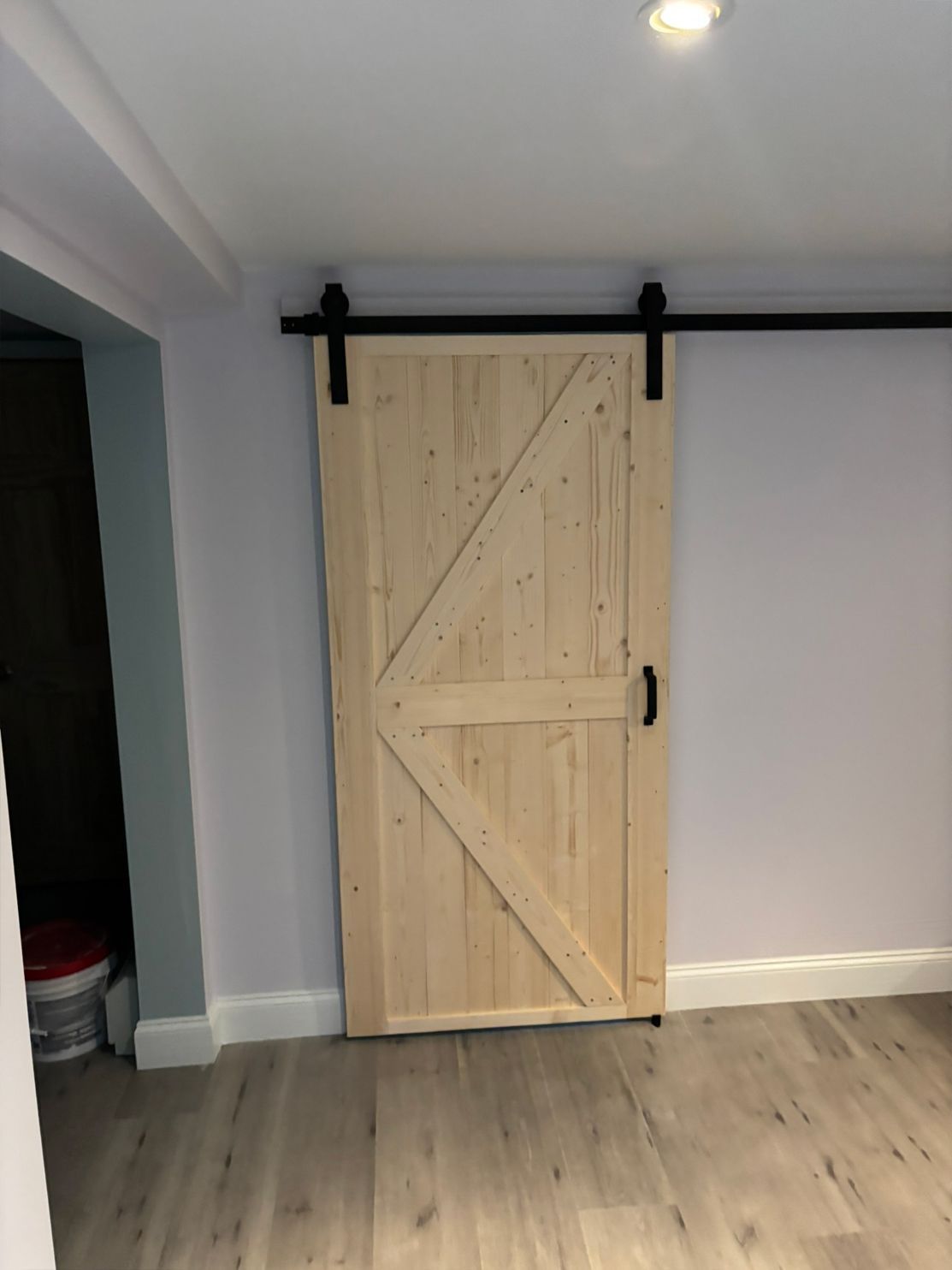 Barn door made of light wood with black hardware, mounted on a wall.
