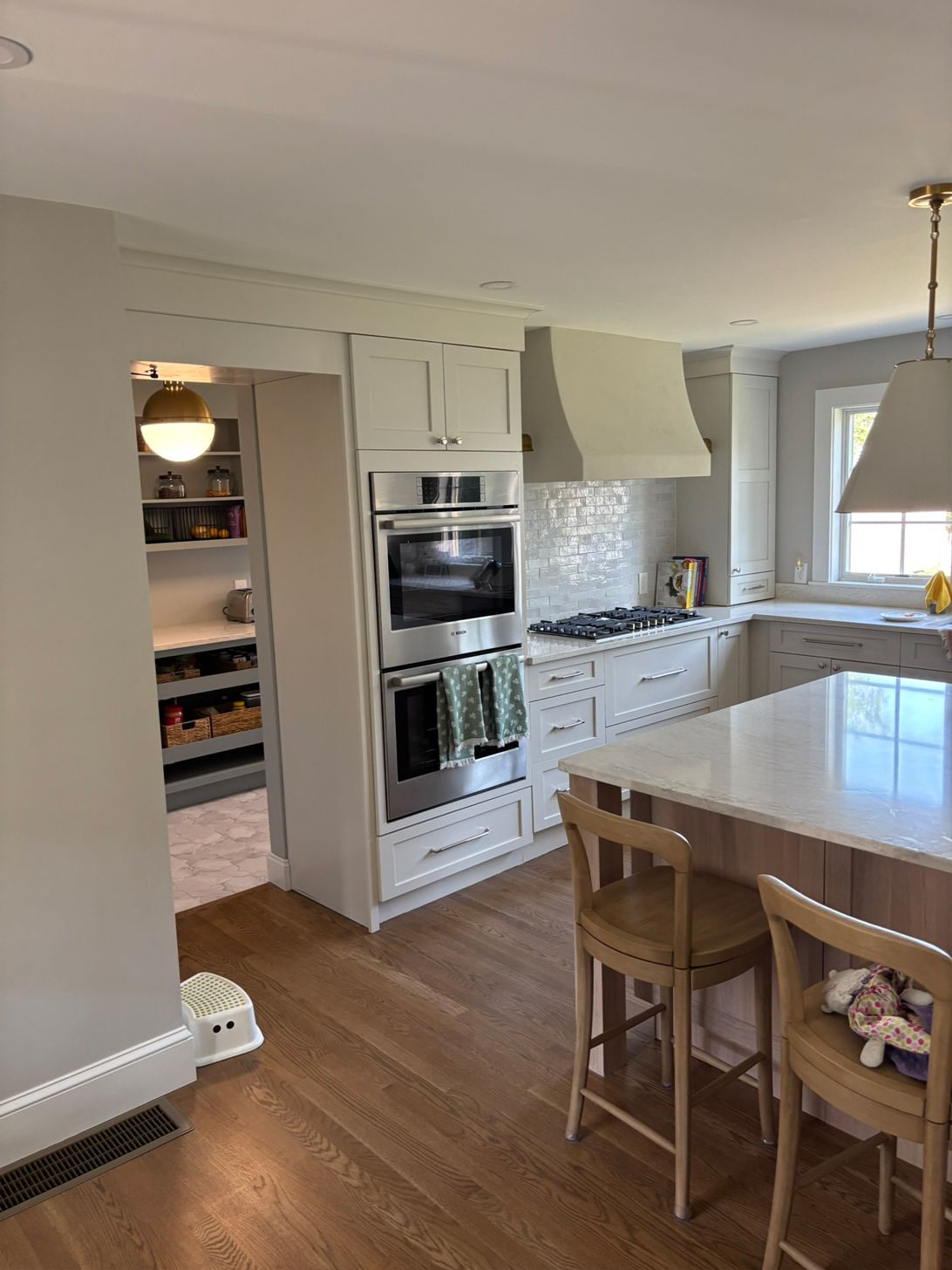Kitchen with white cabinets, stainless steel oven, and a large island with two wooden stools.
