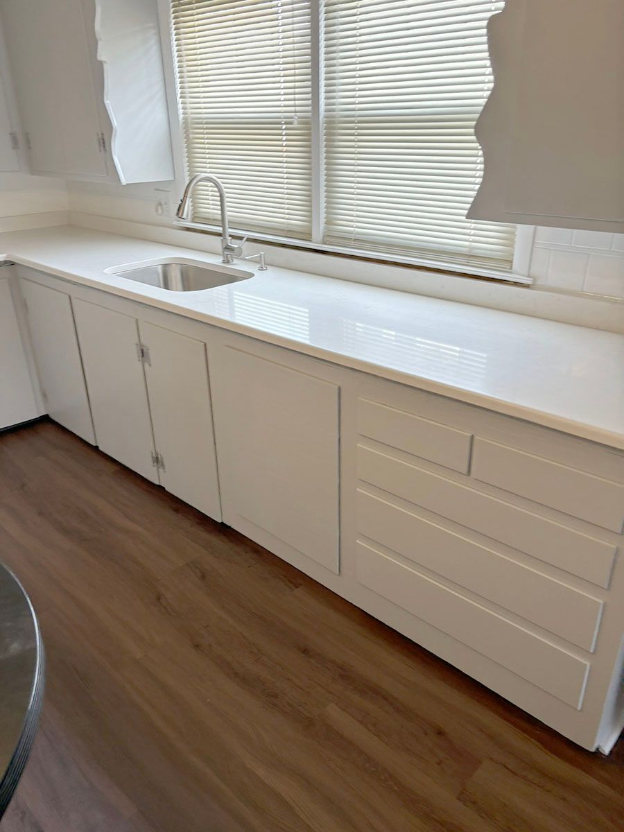 A new kitchen with white cabinets, a sink, and a window