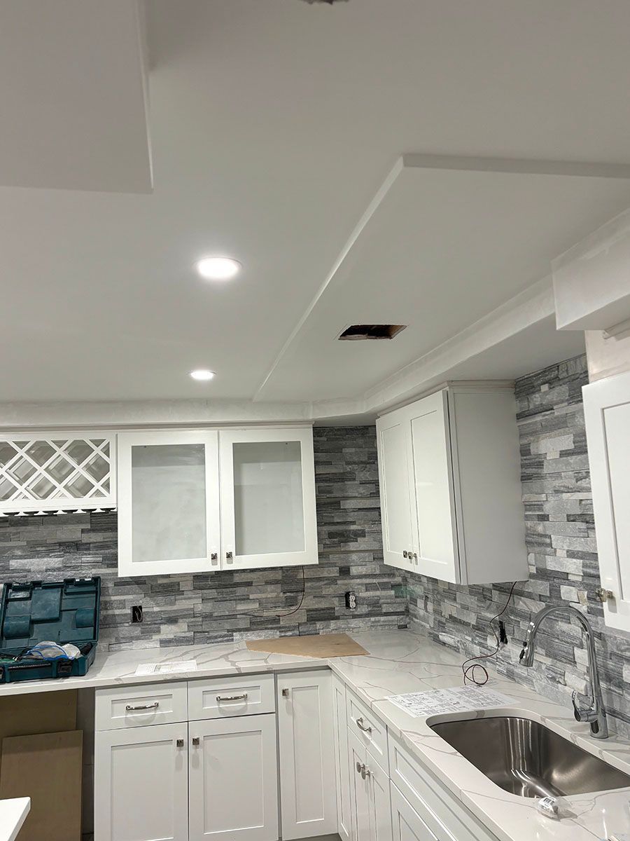 A kitchen with white cabinets and a stainless steel sink
