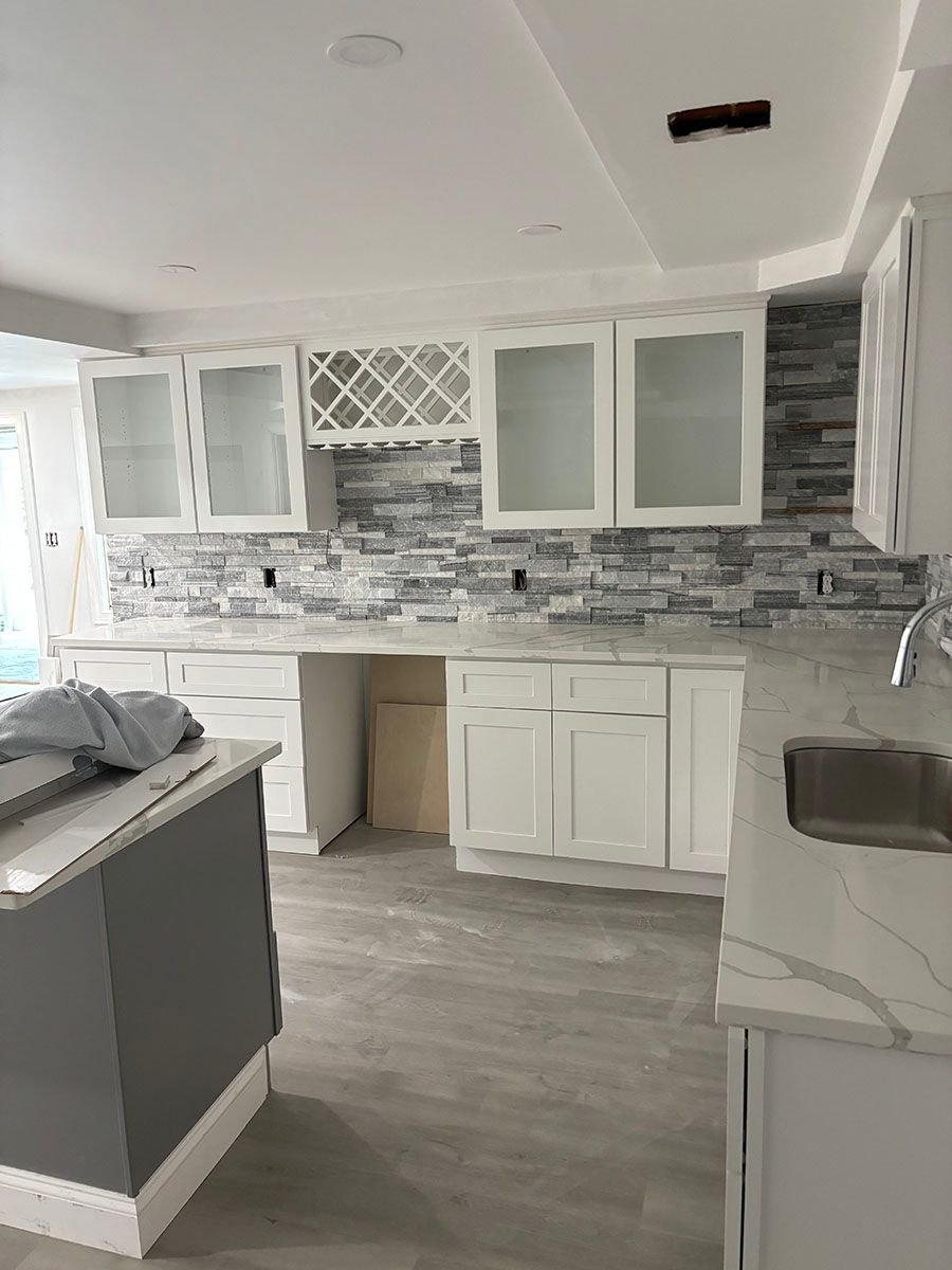 A beautiful kitchen with white cabinets, a sink, and a stone wall