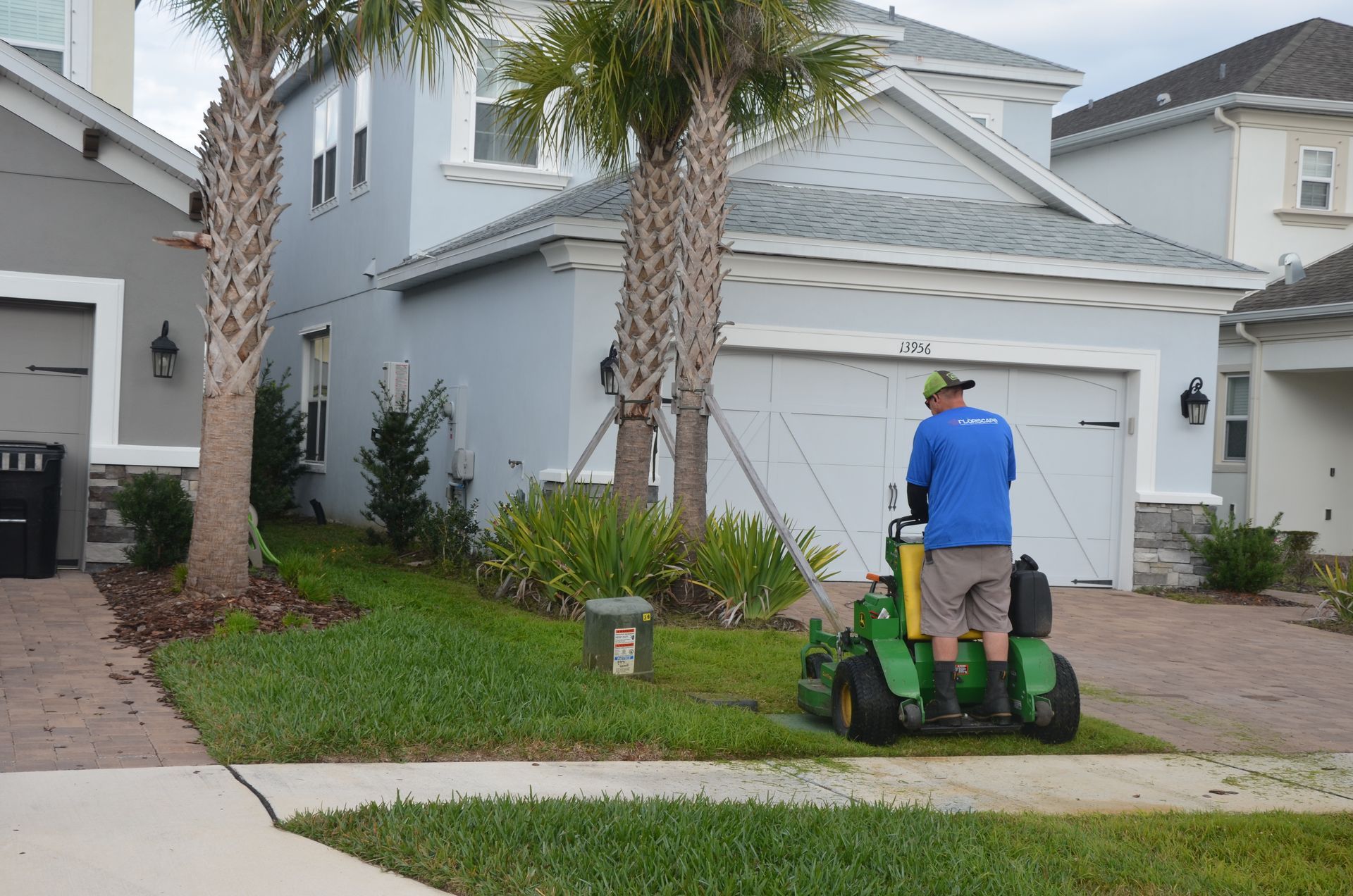 a man is mowing the grass in front of a house
