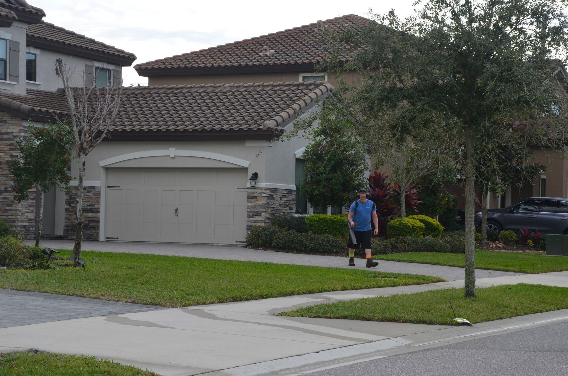 a man is walking down a sidewalk in front of a house