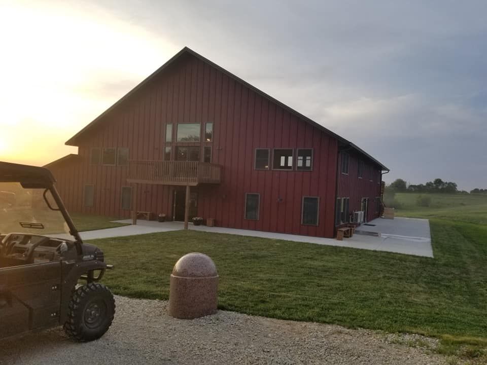 A golf cart is parked in front of a large red barn.