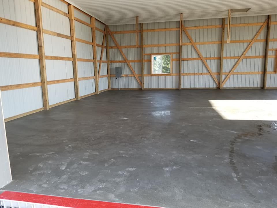 An empty garage with a concrete floor and wooden walls.