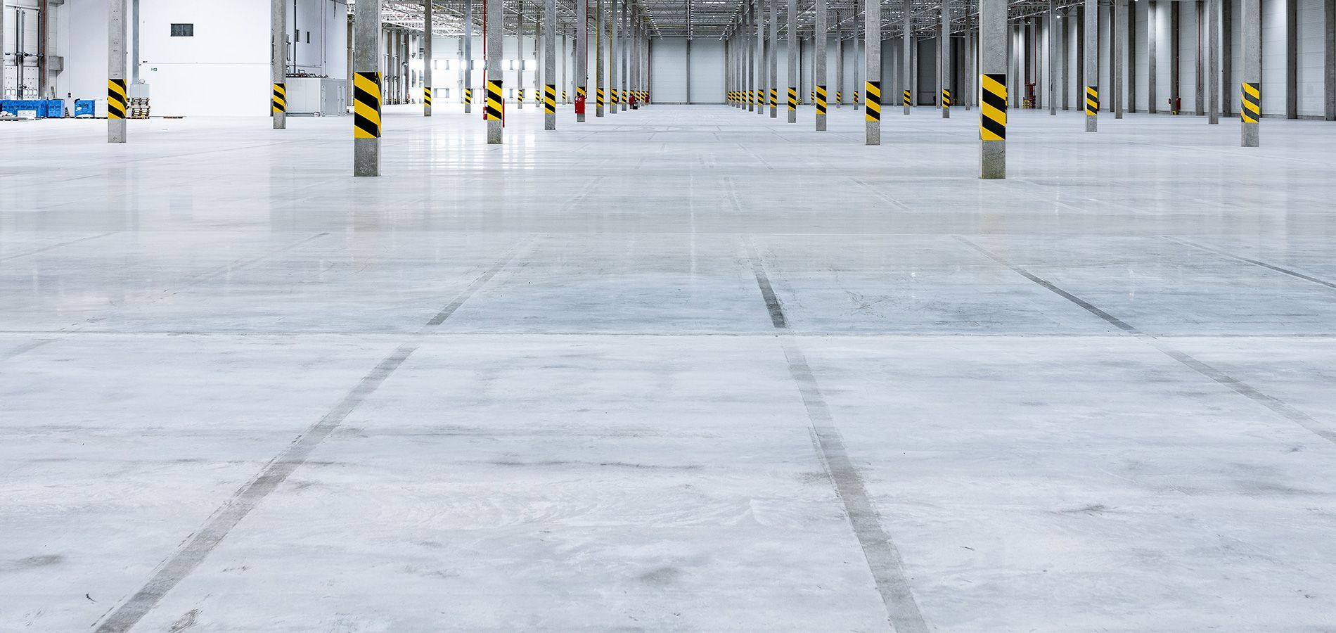 An empty warehouse with concrete floors and yellow poles.