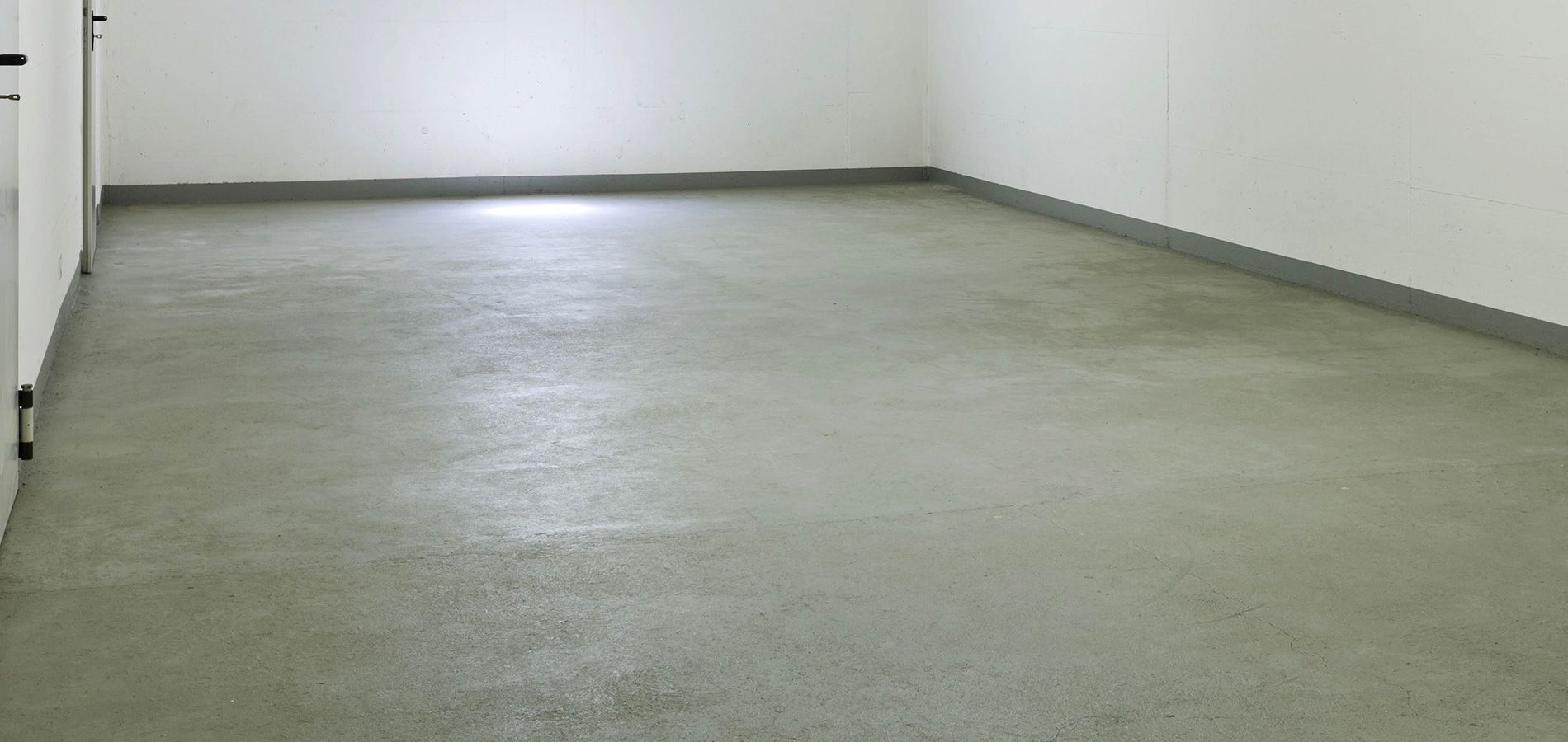 An empty garage with a concrete floor and white walls.