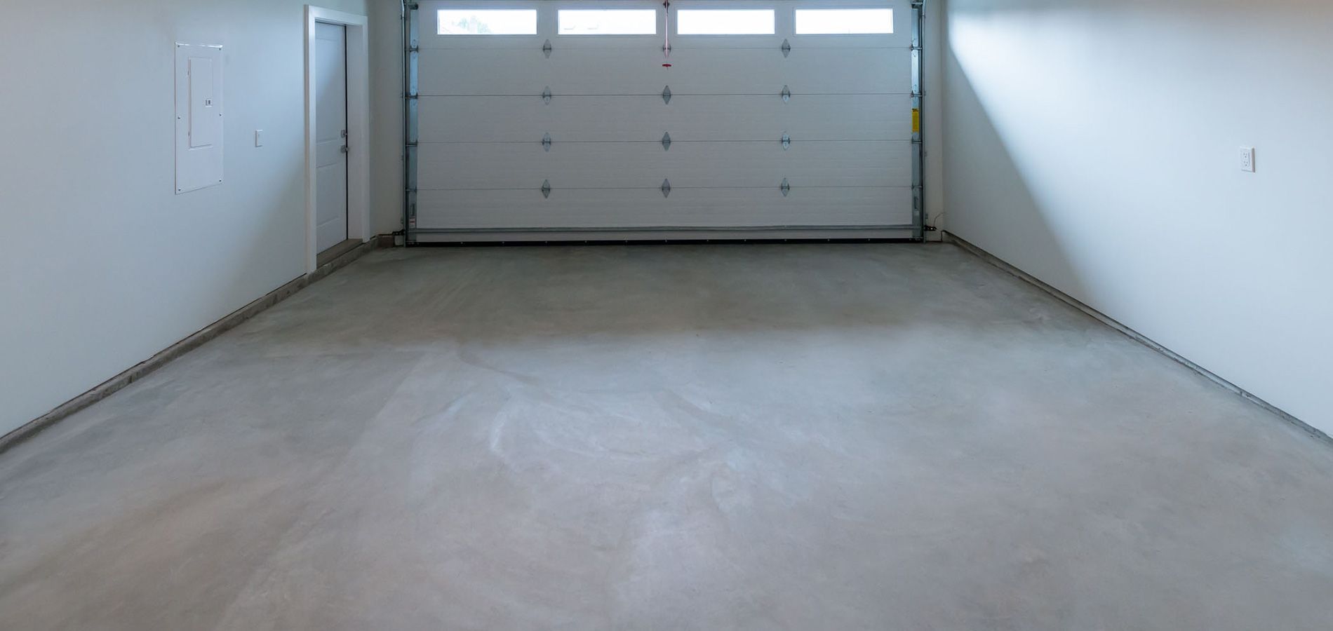 An empty garage with a garage door open and a concrete floor.