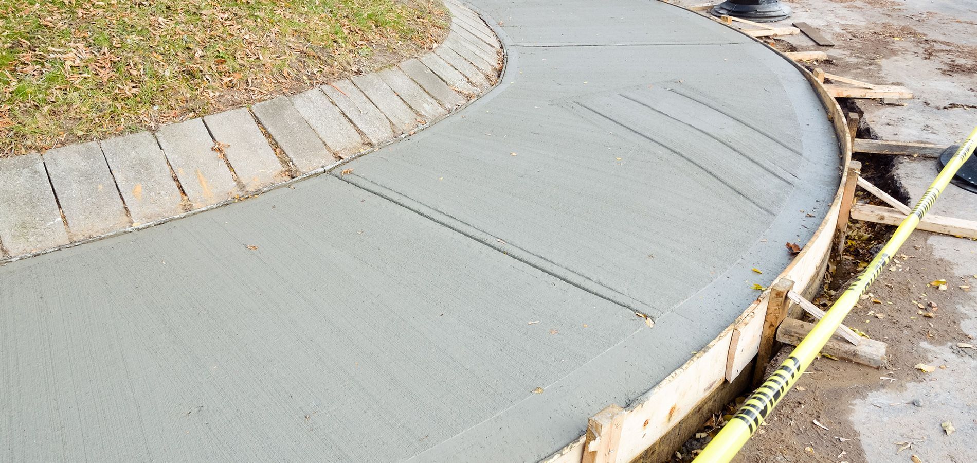 A concrete sidewalk is being built with a yellow tape around it.