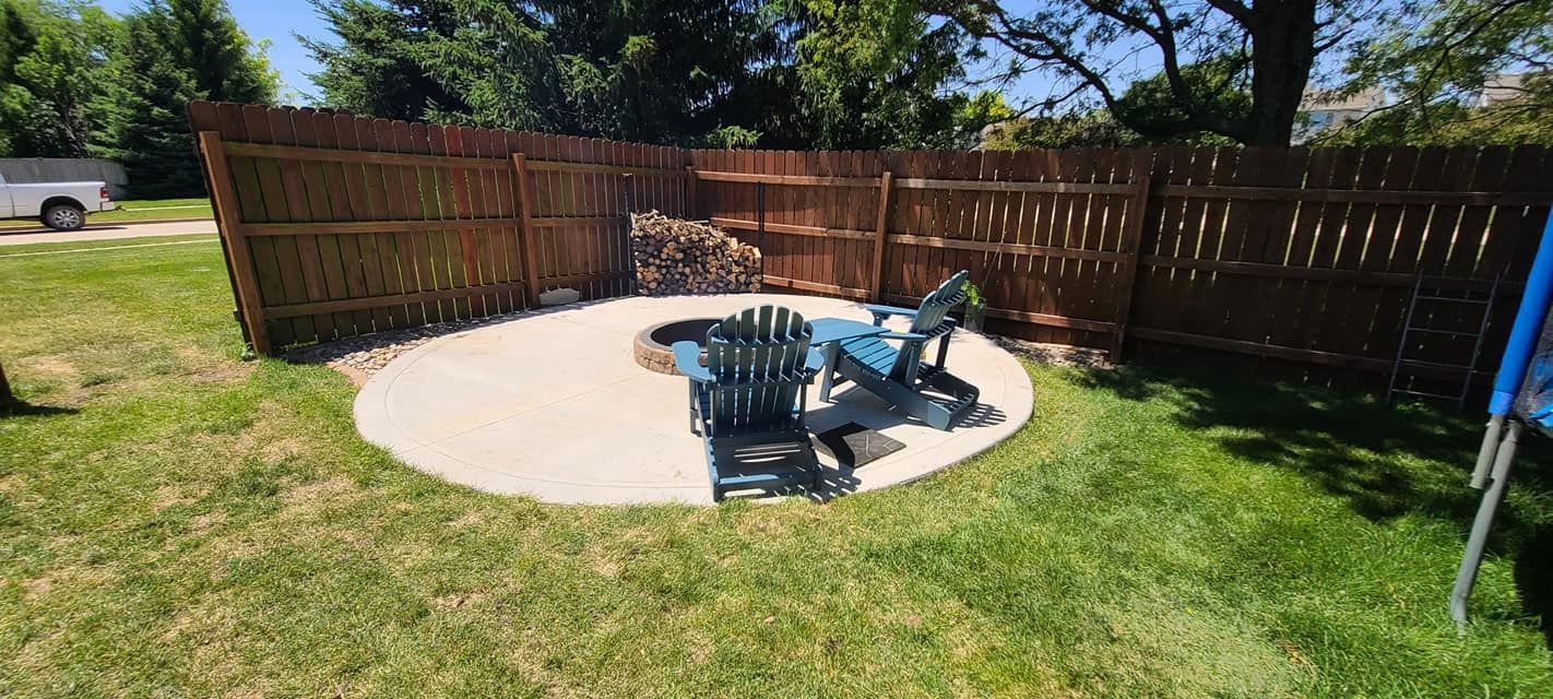 A patio with two chairs and a fence in the backyard.