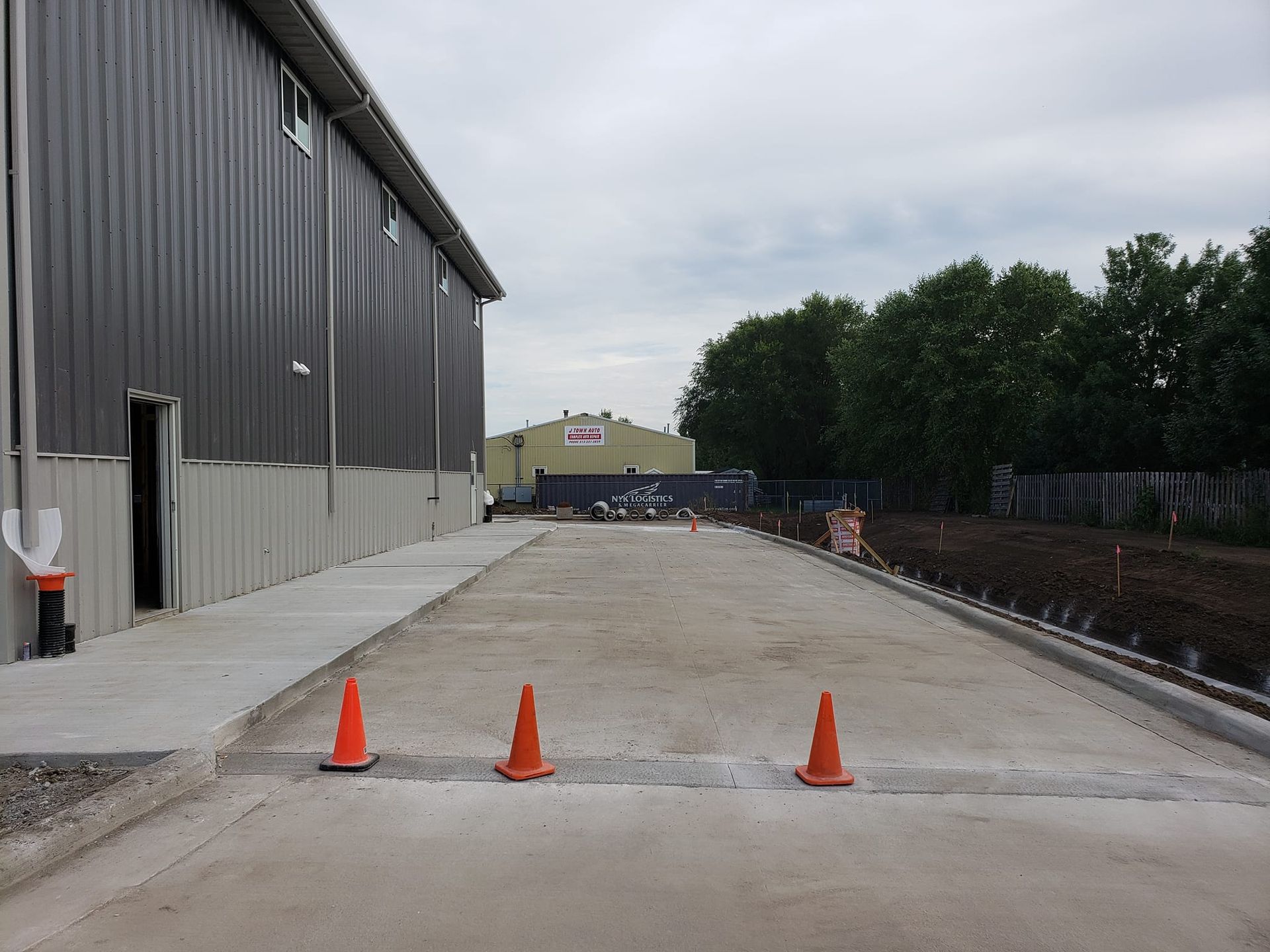 A concrete driveway with orange cones on the side of it in front of a building.
