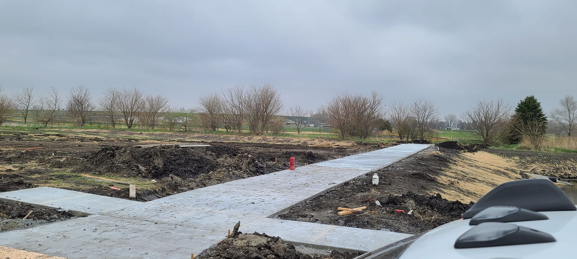 A car is parked on the side of a dirt road in a field.