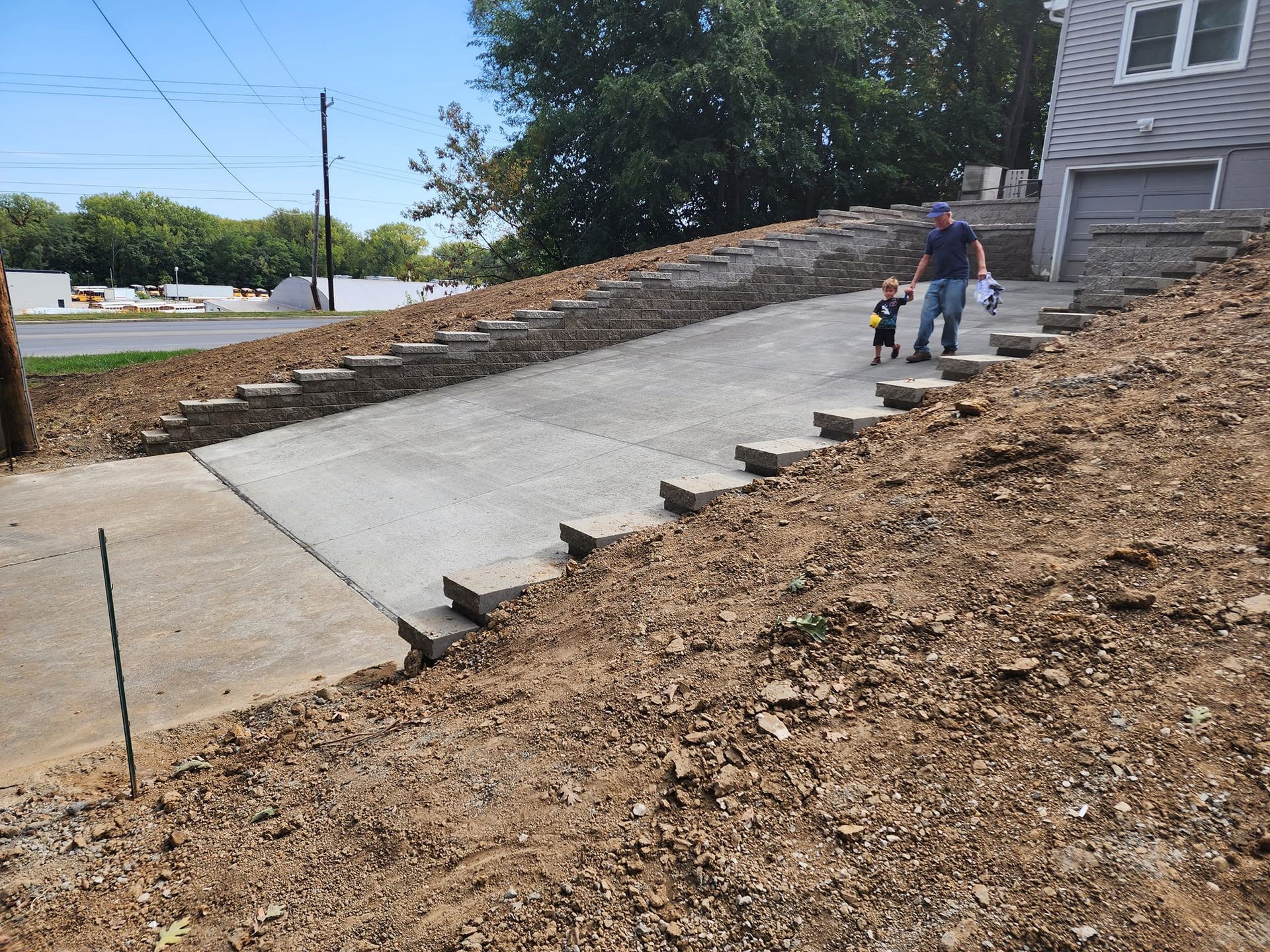 A man and a child are walking down a concrete driveway