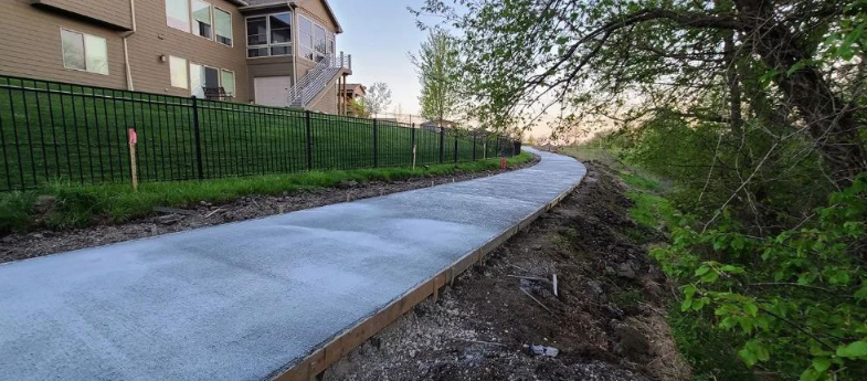 A concrete walkway is being built next to a fence.
