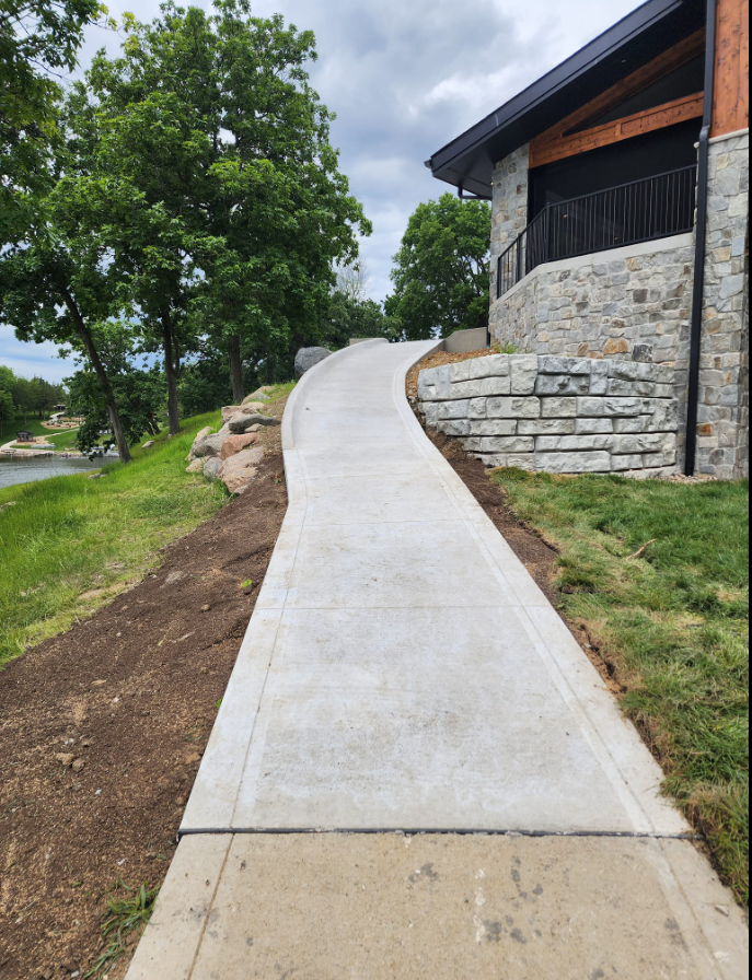 A concrete walkway leading to a stone building