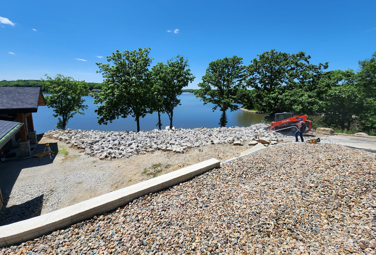 A large pile of gravel is sitting next to a body of water