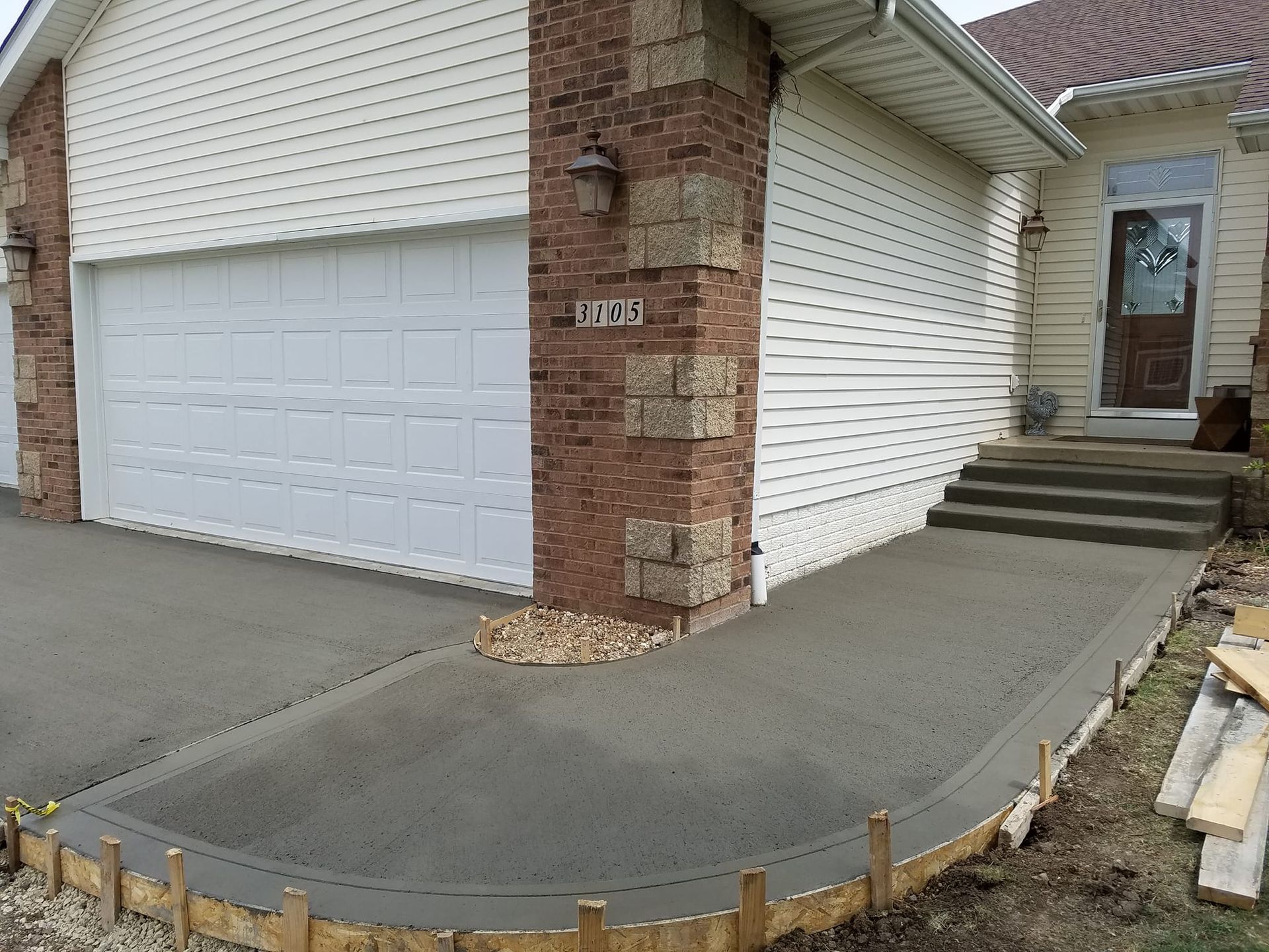 A concrete walkway is being built in front of a house
