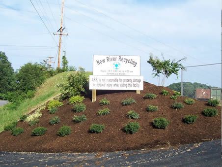 A sign for new river recycling is sitting on top of a hill