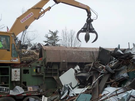 A yellow crane is lifting a pile of scrap metal