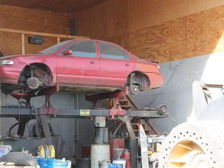 A red car is on a lift in a garage