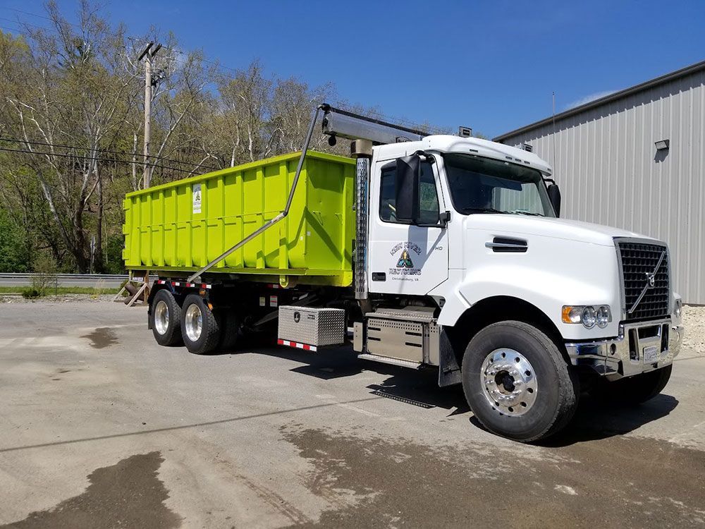A white dump truck with a green trailer is parked in a parking lot.