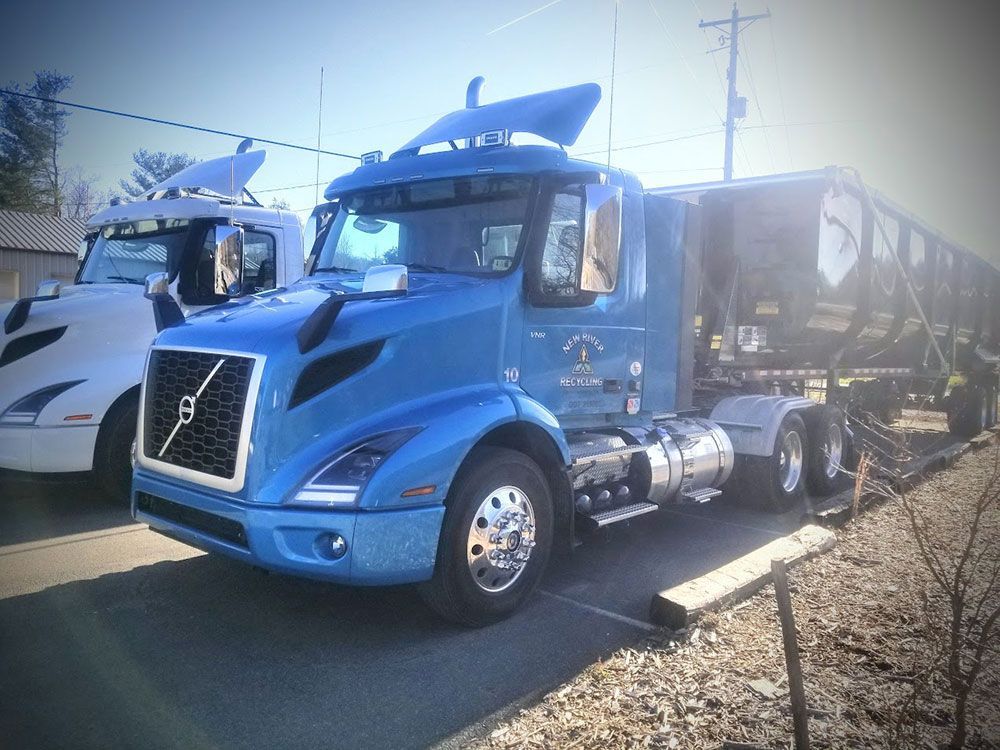 A blue semi truck is parked next to a white semi truck.