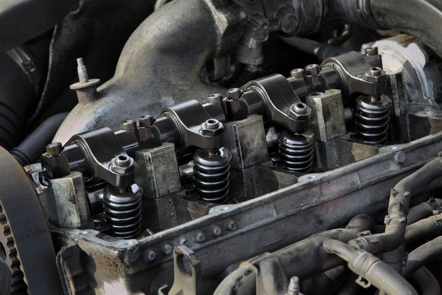 Close-up of an exposed car engine cylinder head with valves and springs visible