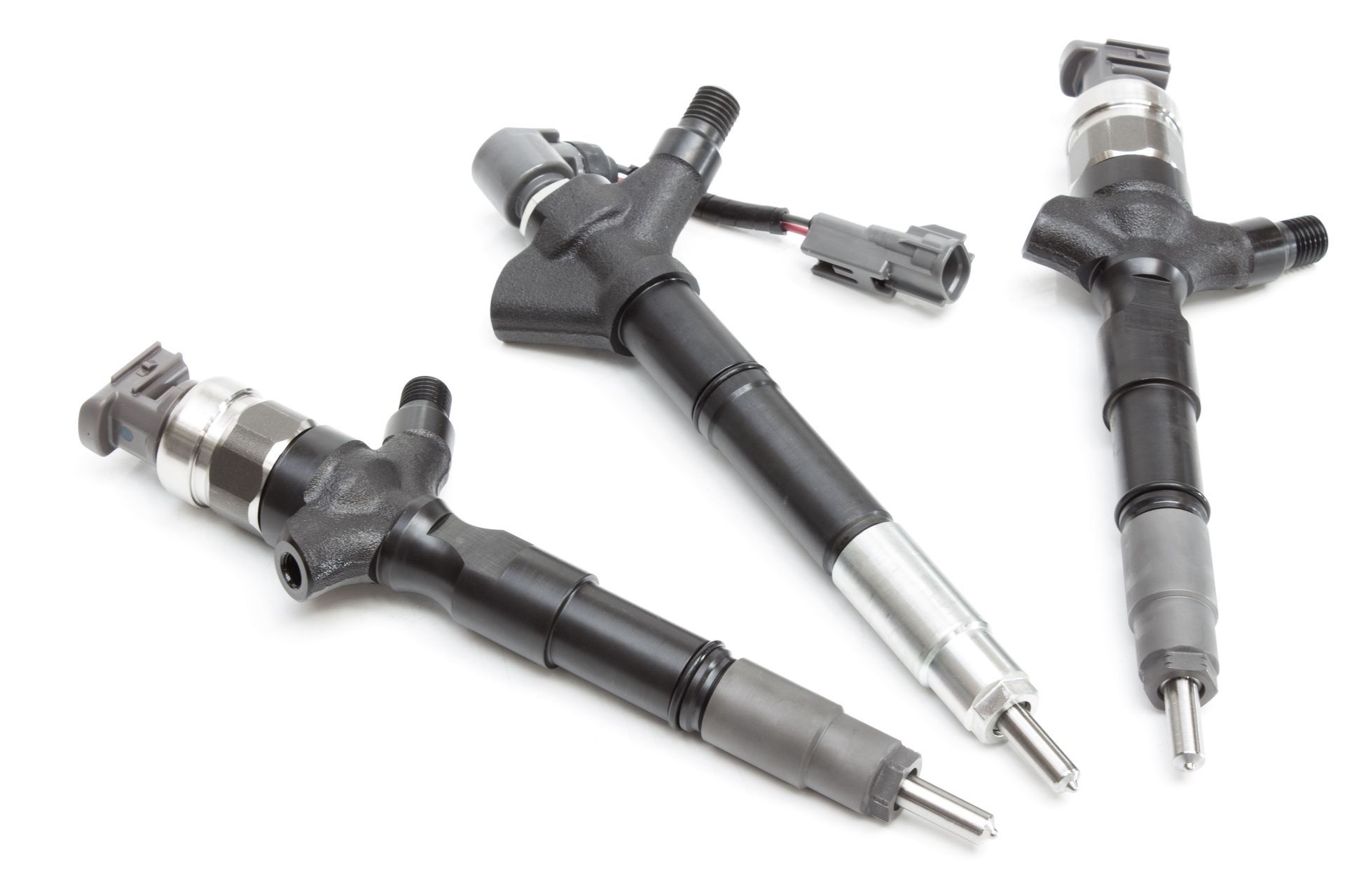 Three black and silver fuel injectors arranged on a white background