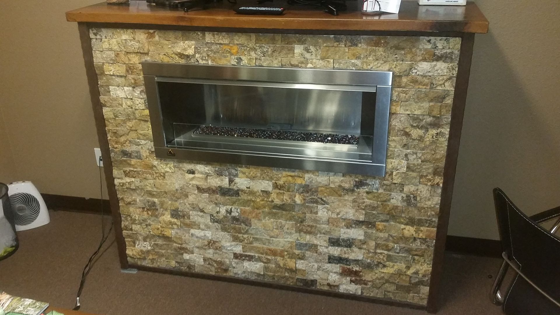 A fireplace with a brick wall and a stainless steel frame in a room.
