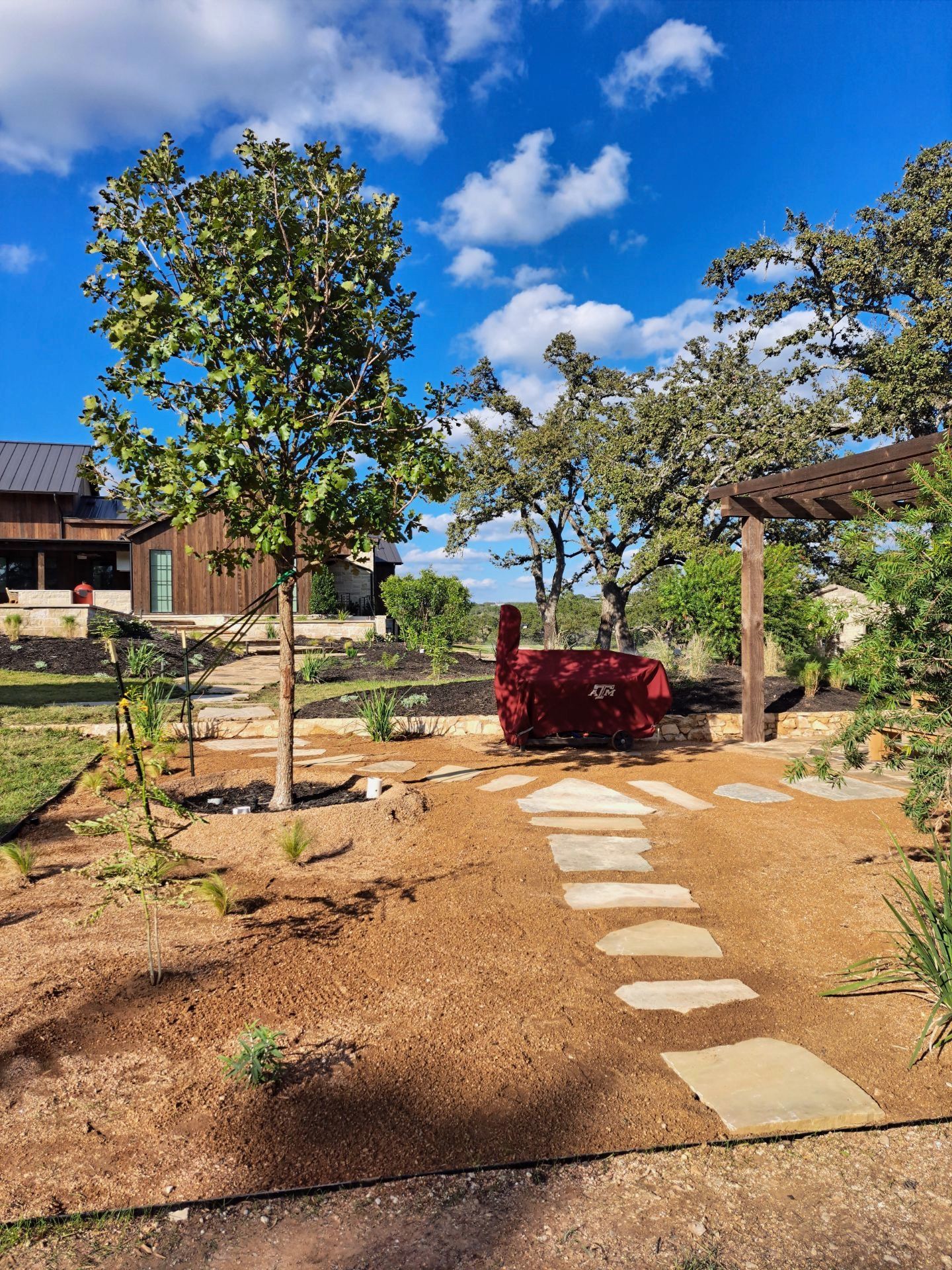 A stone walkway leading to a house with trees in the background.