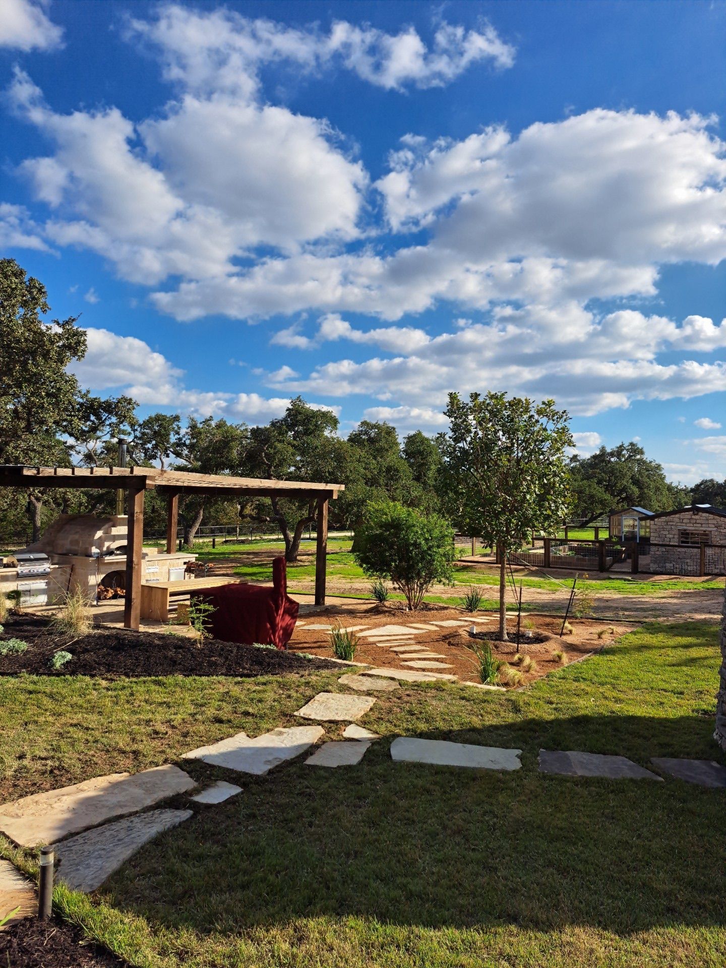 A lush green yard with a pergola and a stone walkway.