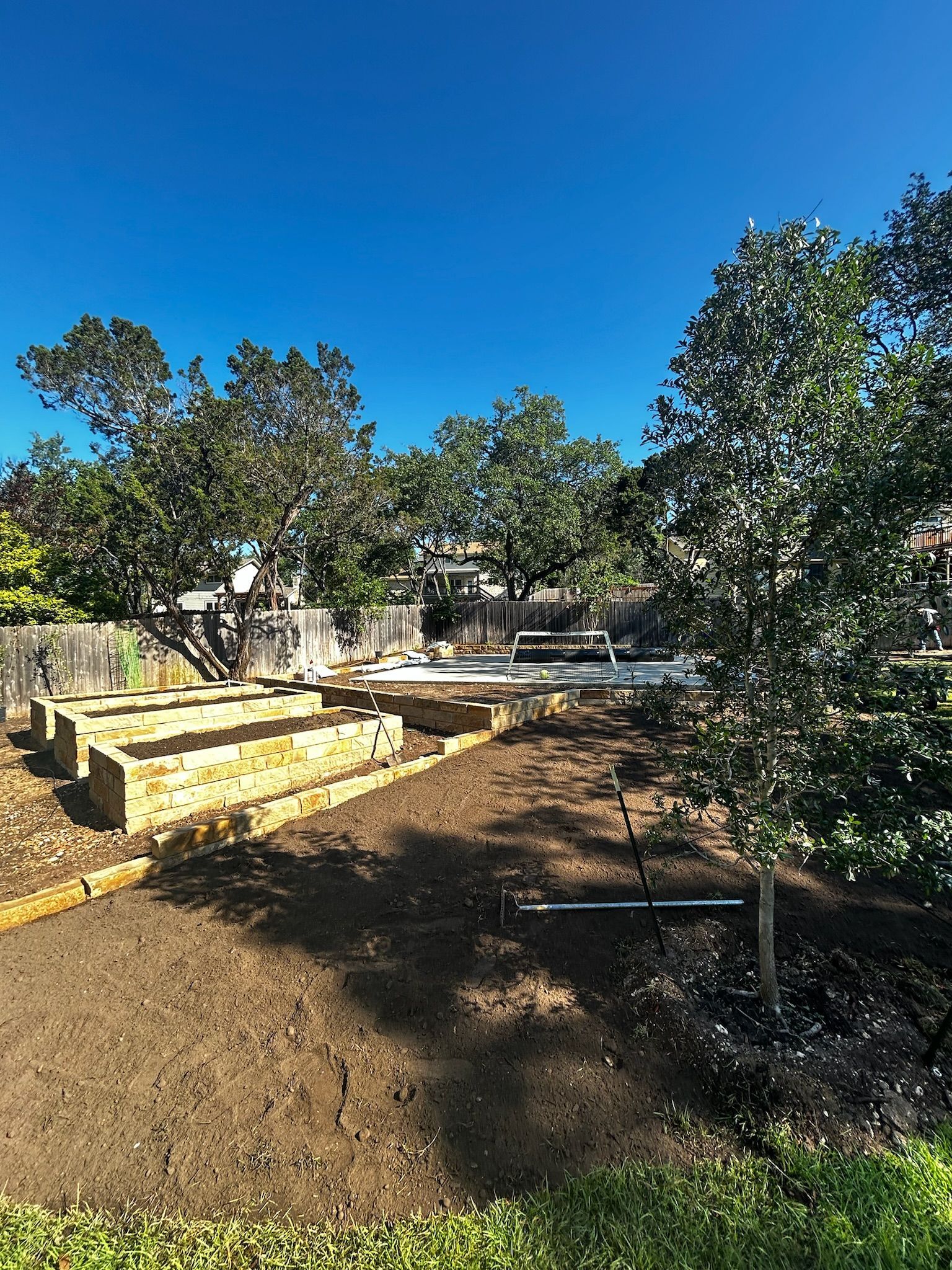 A large dirt field with trees in the background and a blue sky in the background.