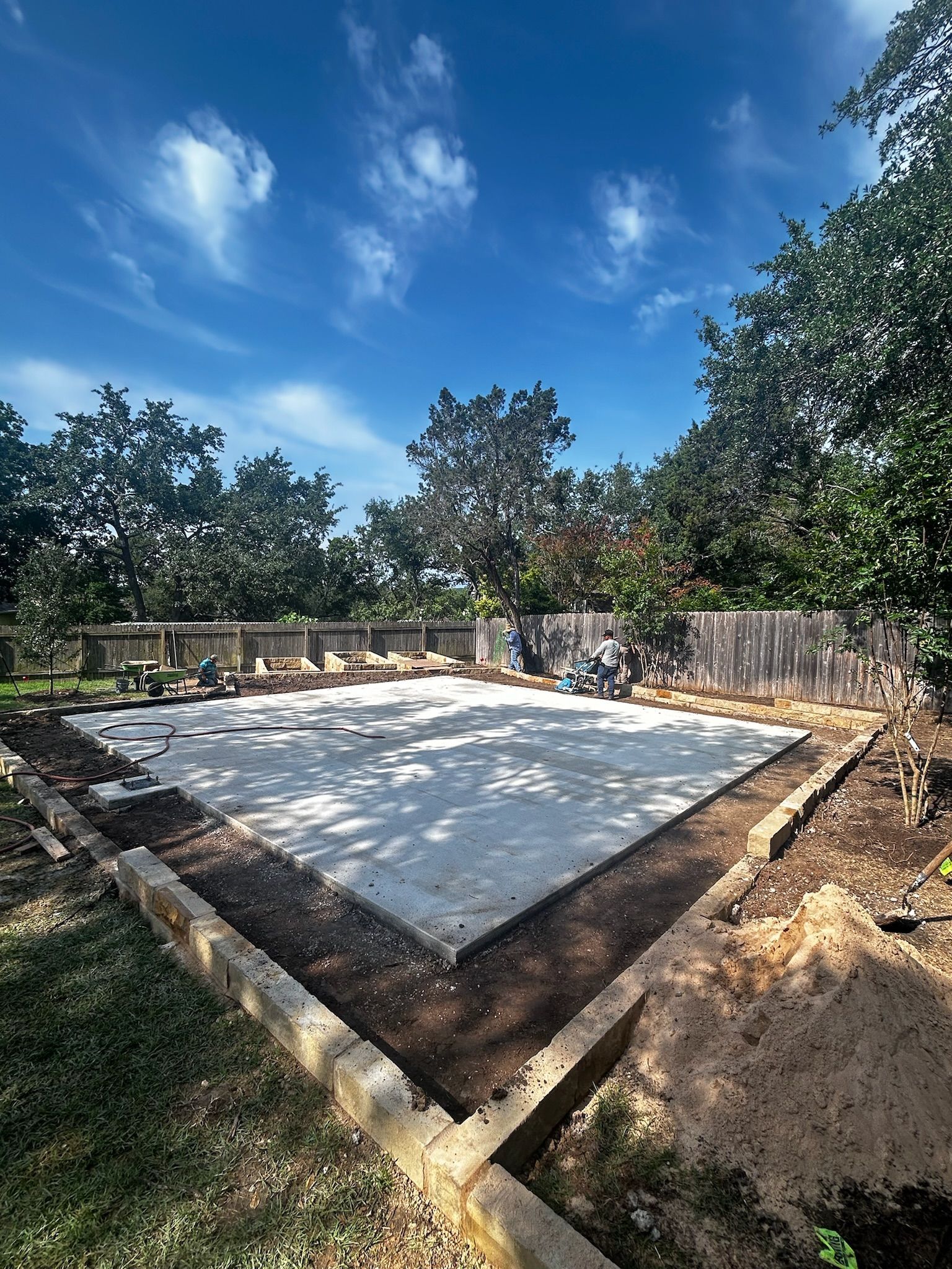 A concrete base for a house is being built in a backyard.