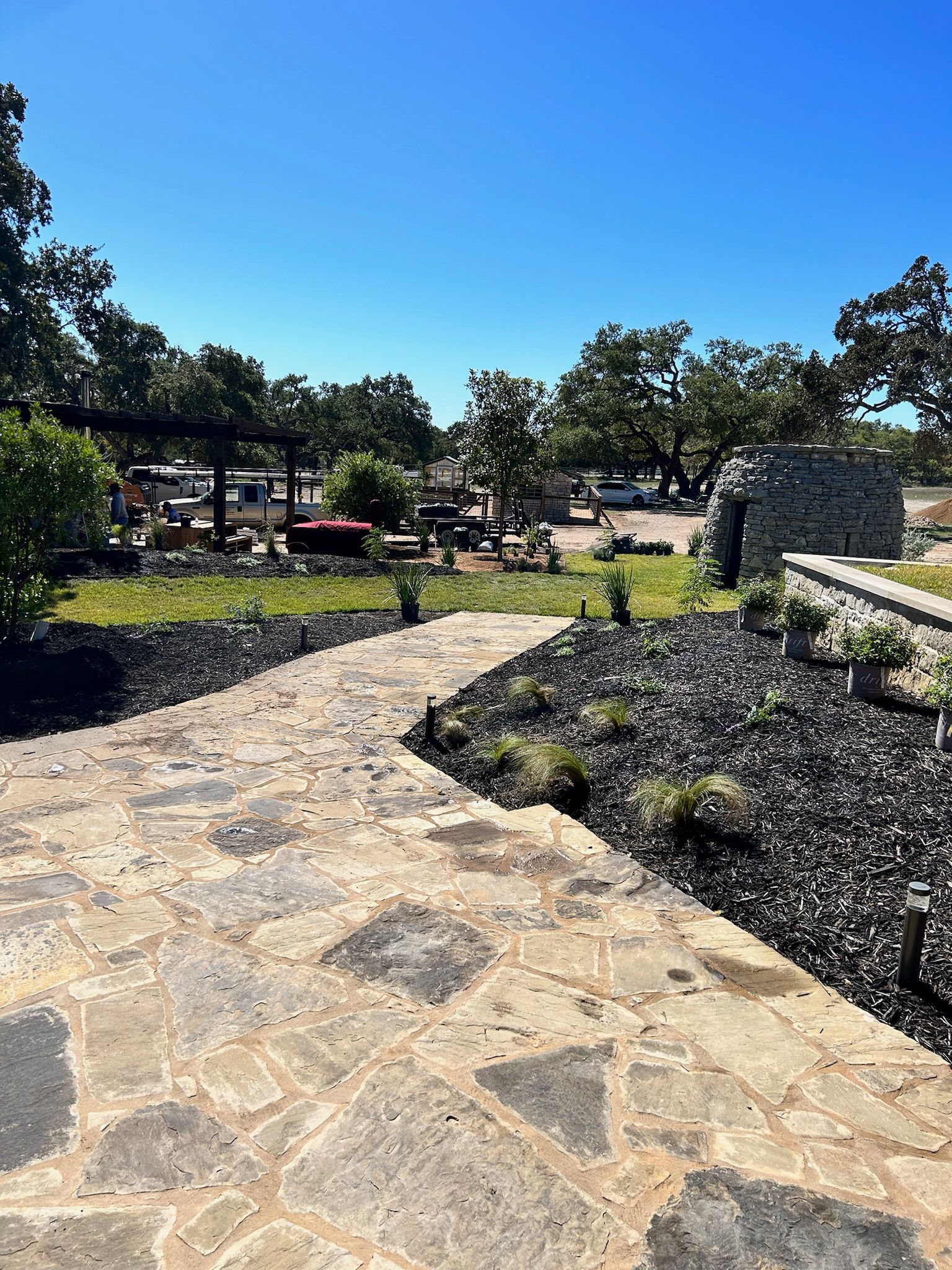 A stone walkway leading to a park with trees and bushes on a sunny day.