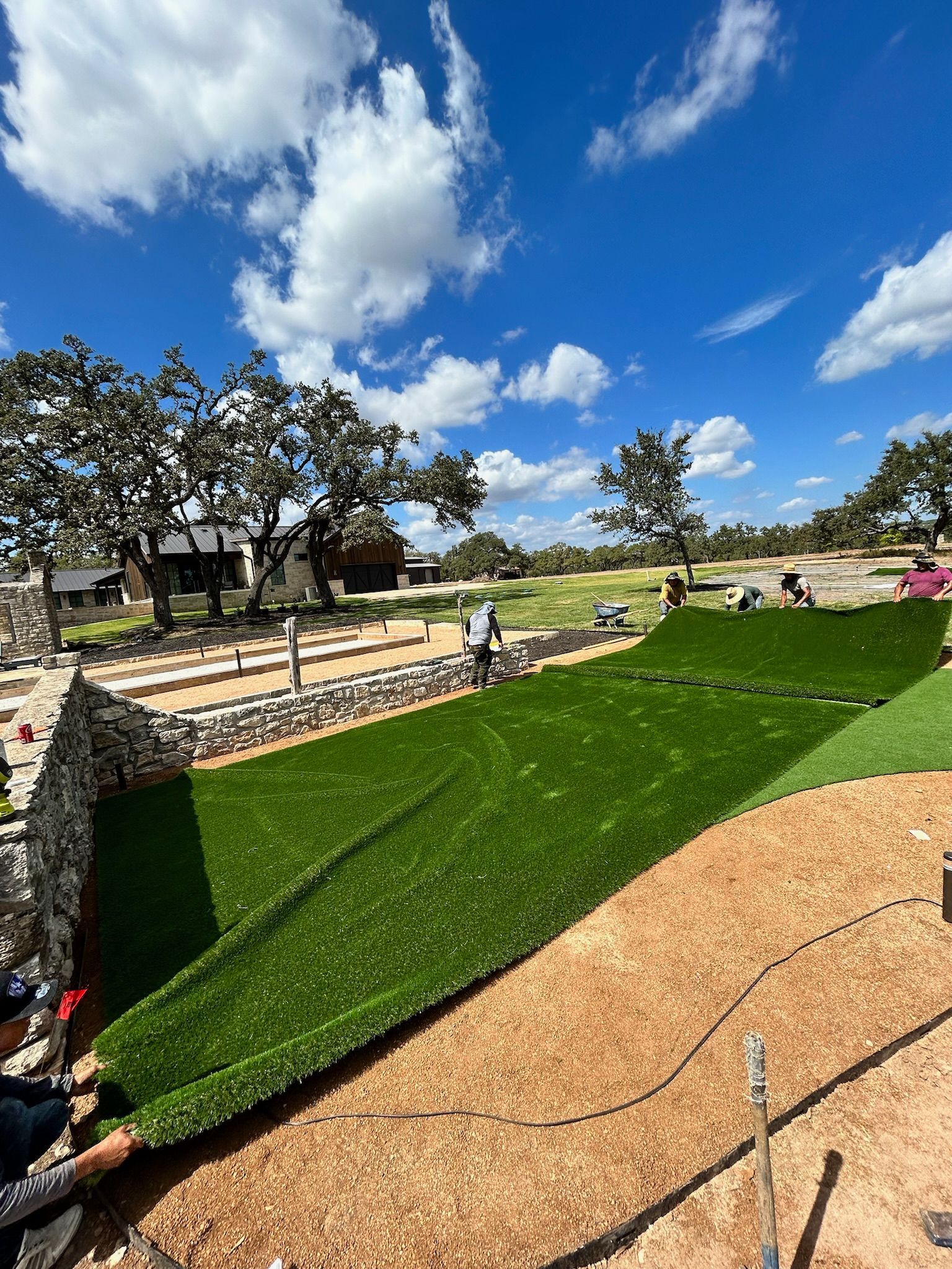 A large amount of artificial grass is being rolled out in a field.