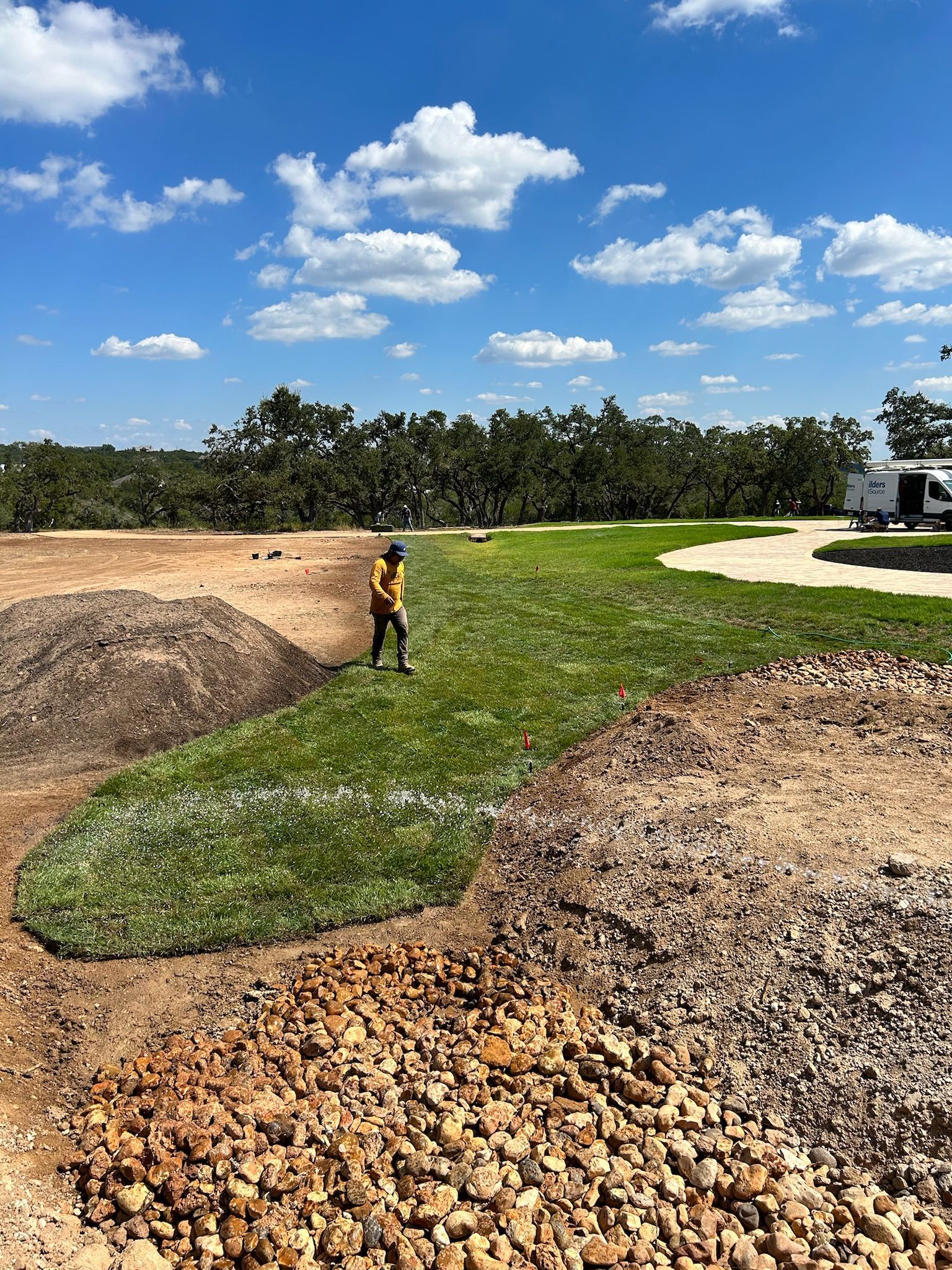 A man is standing in a field of grass and rocks.