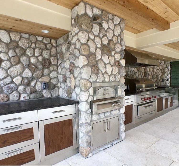 A kitchen with stone walls and stainless steel cabinets