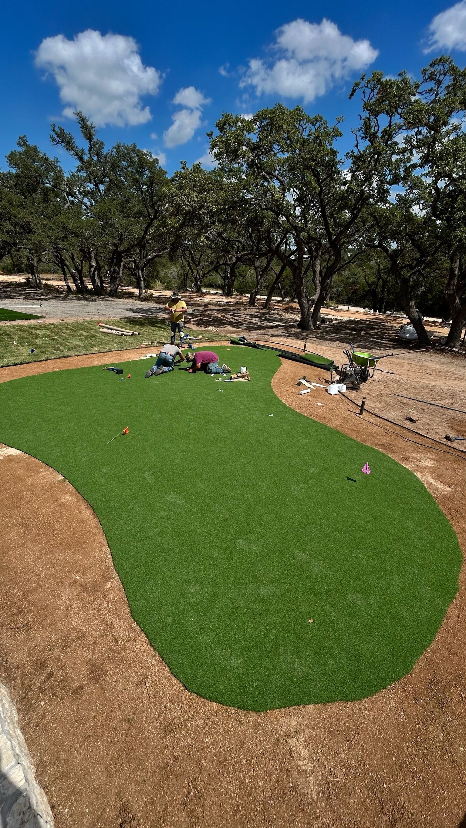 A putting green is being built in the middle of a field with trees in the background.