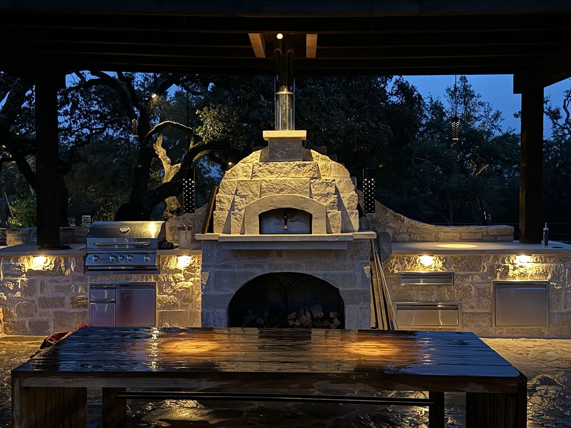 An outdoor kitchen with a pizza oven and a table