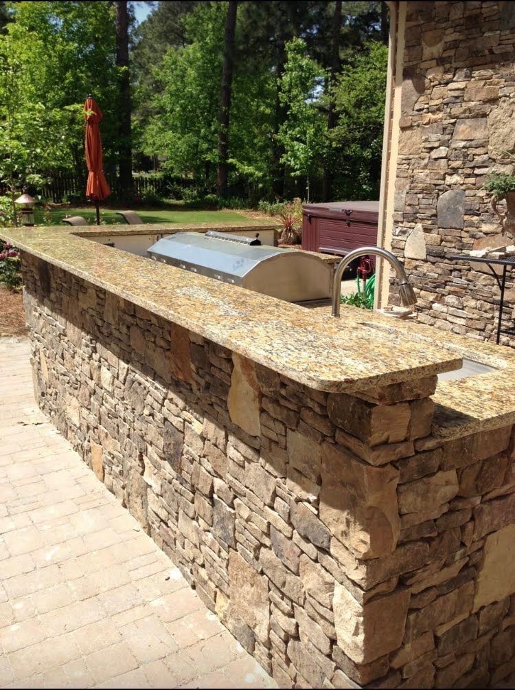 A stone counter with a sink and a grill on it